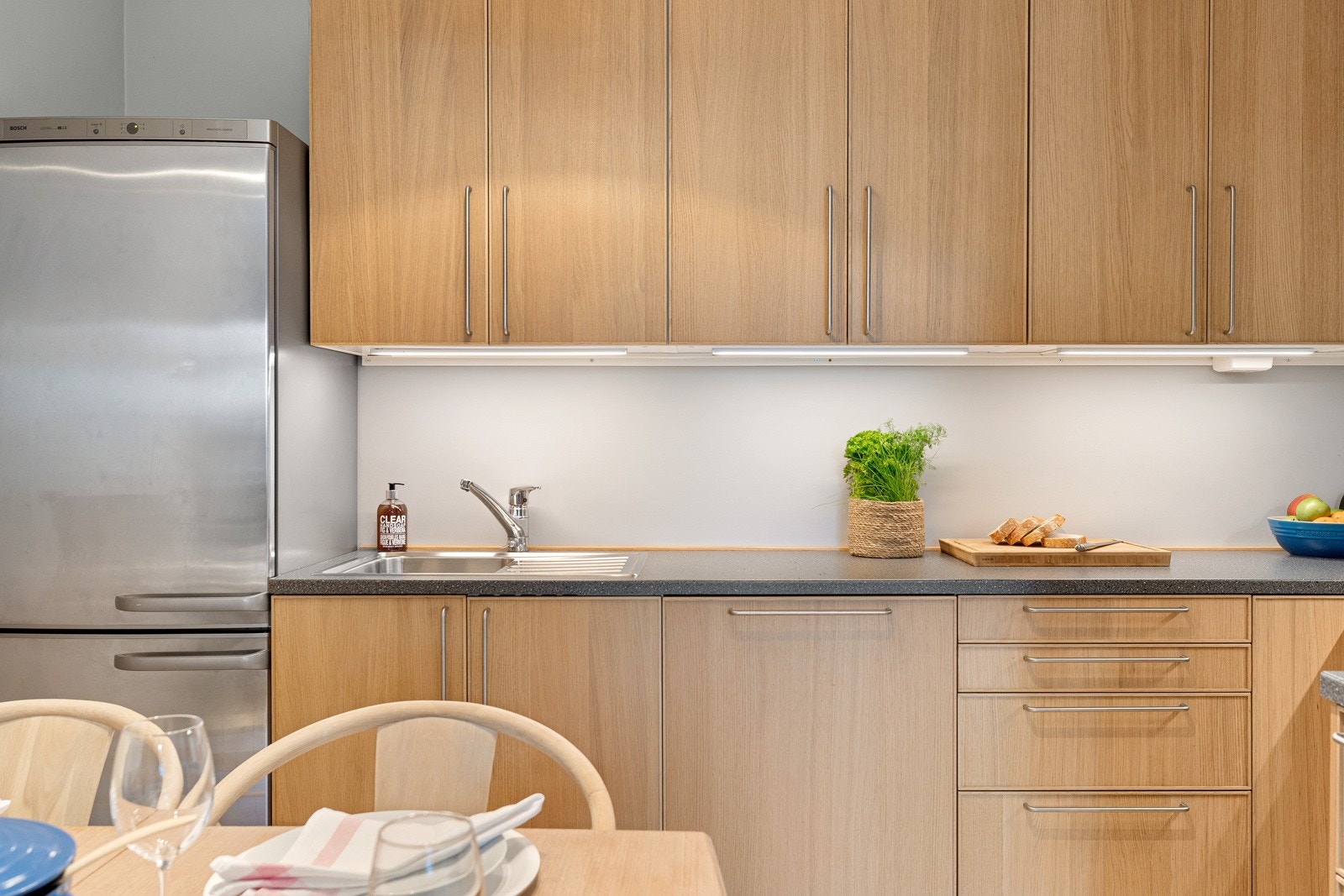 Integrerte hvitevarer som oppvaskmaskin fra Bosch og avtrekksvifte over komfyr. Opplegg for kjøl/frys Galleribilde