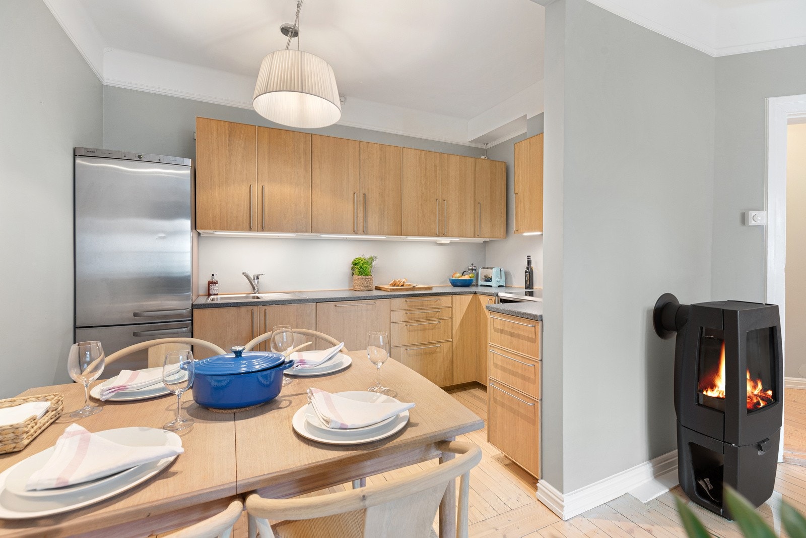 Kjøkkeninnredning med finérte fronter, stålhåndtak og overskap med benkebelysning Galleribilde