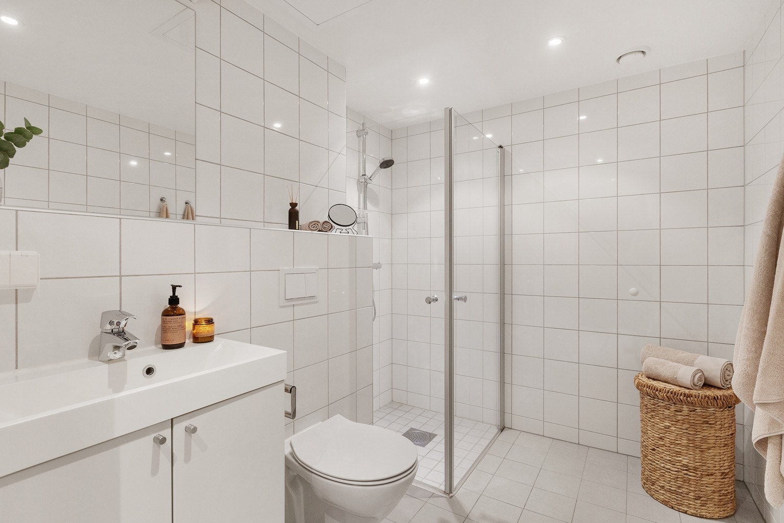 Romslig baderom med hjørnedusj, servant og vegghengt sisterne. Galleribilde