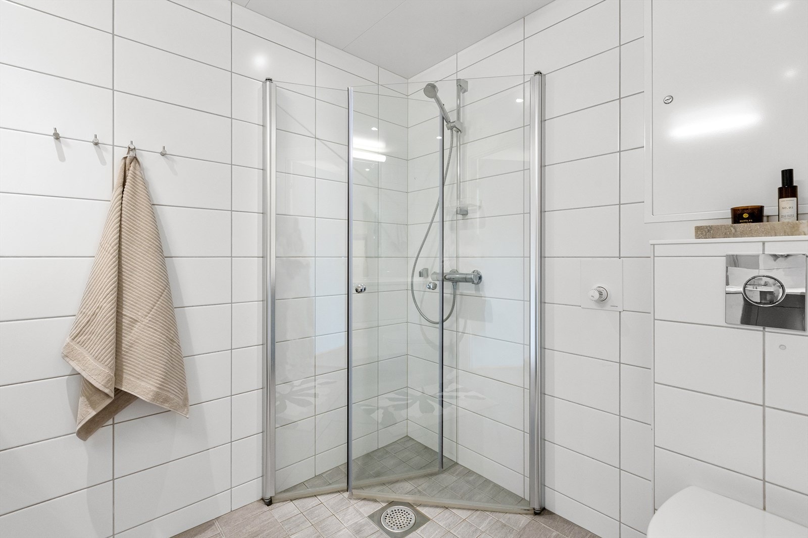 Badet består av: Vegghengt toalett, dusjhjørne med glassdører. Laminat benkeplate med servant og ettgreps blandebatteri. Under servanten er det en skuffeseksjon med slette fronter. Opplegg for vaskemaskin. Galleribilde