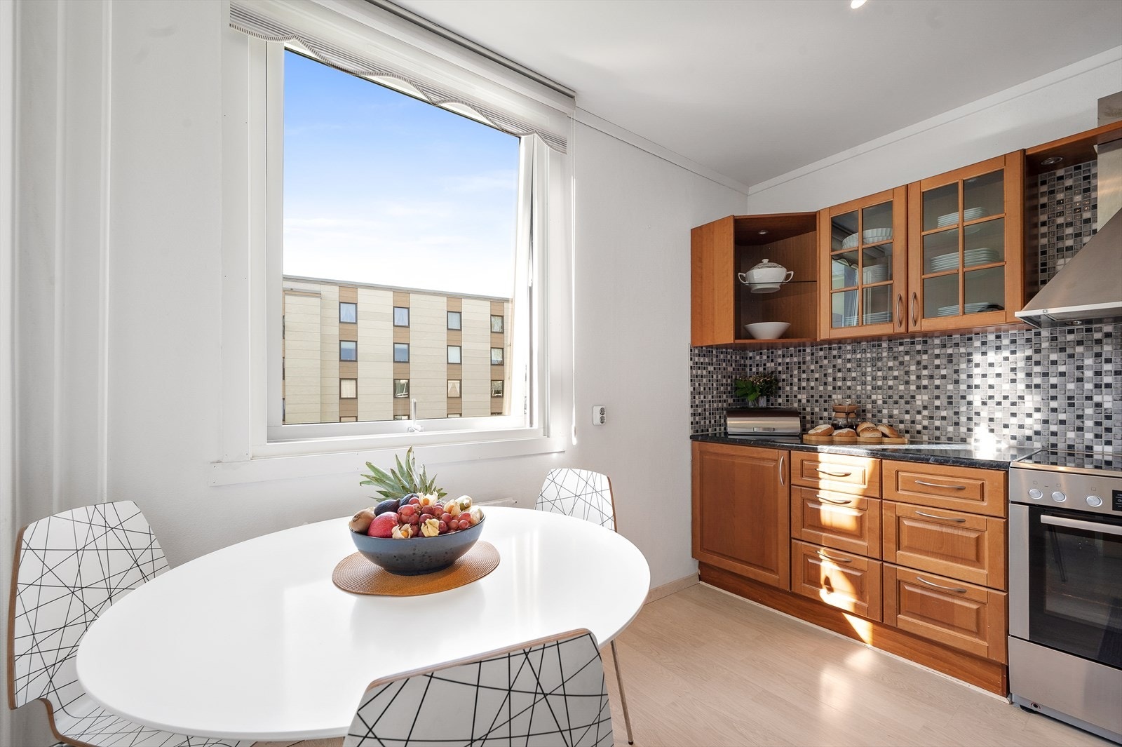 Kjøkken i eget rom med plass til frokostbord ved et stort vindu som bidrar til en lys og trivelig atmosfære Galleribilde