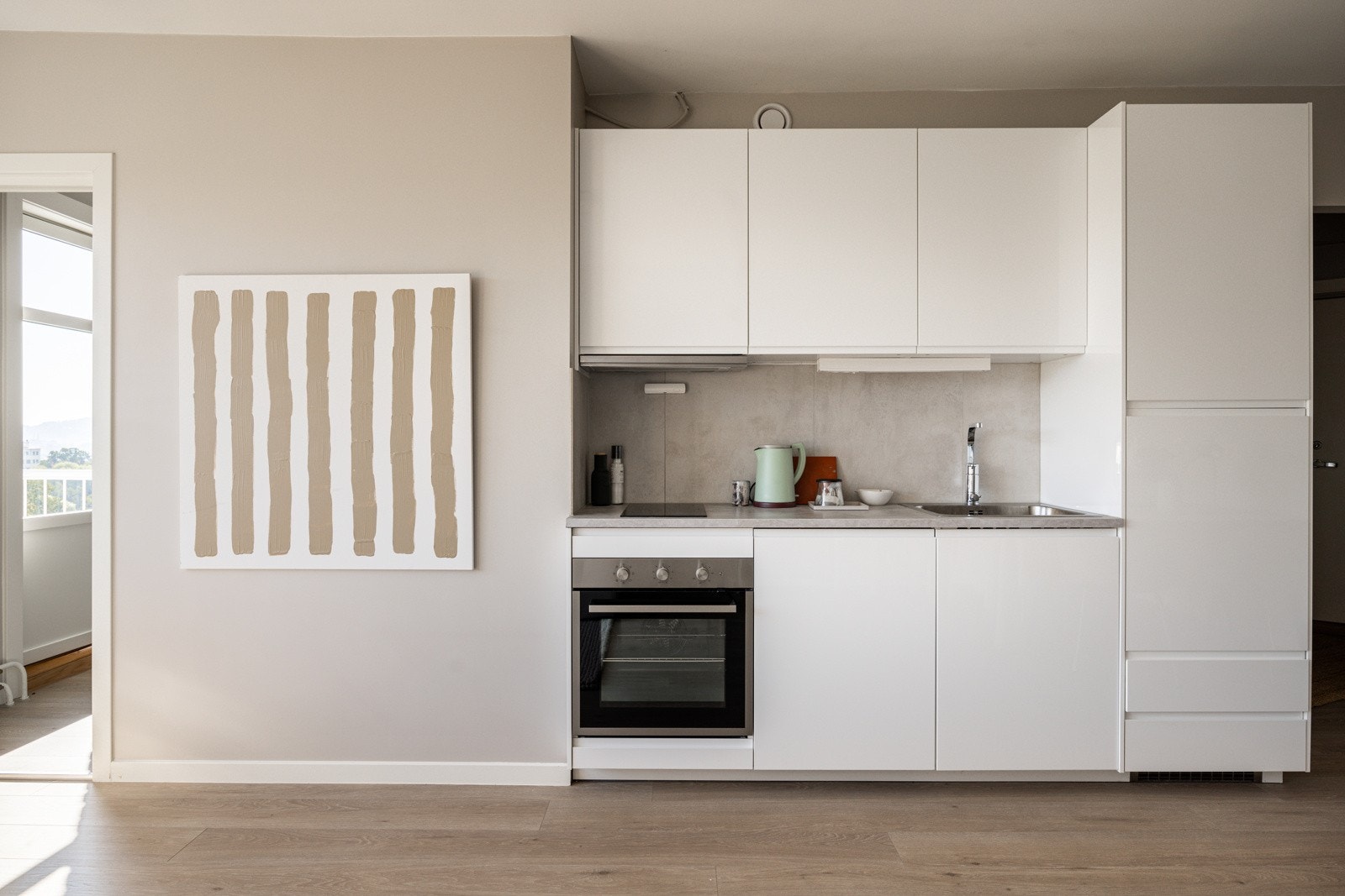 Stilrent og moderne Ikea-kjøkken fra 2020. Innredningen har hvite glatte fronter med integrerte grep og laminert benkeplate med nedfelt oppvaskkum. Galleribilde