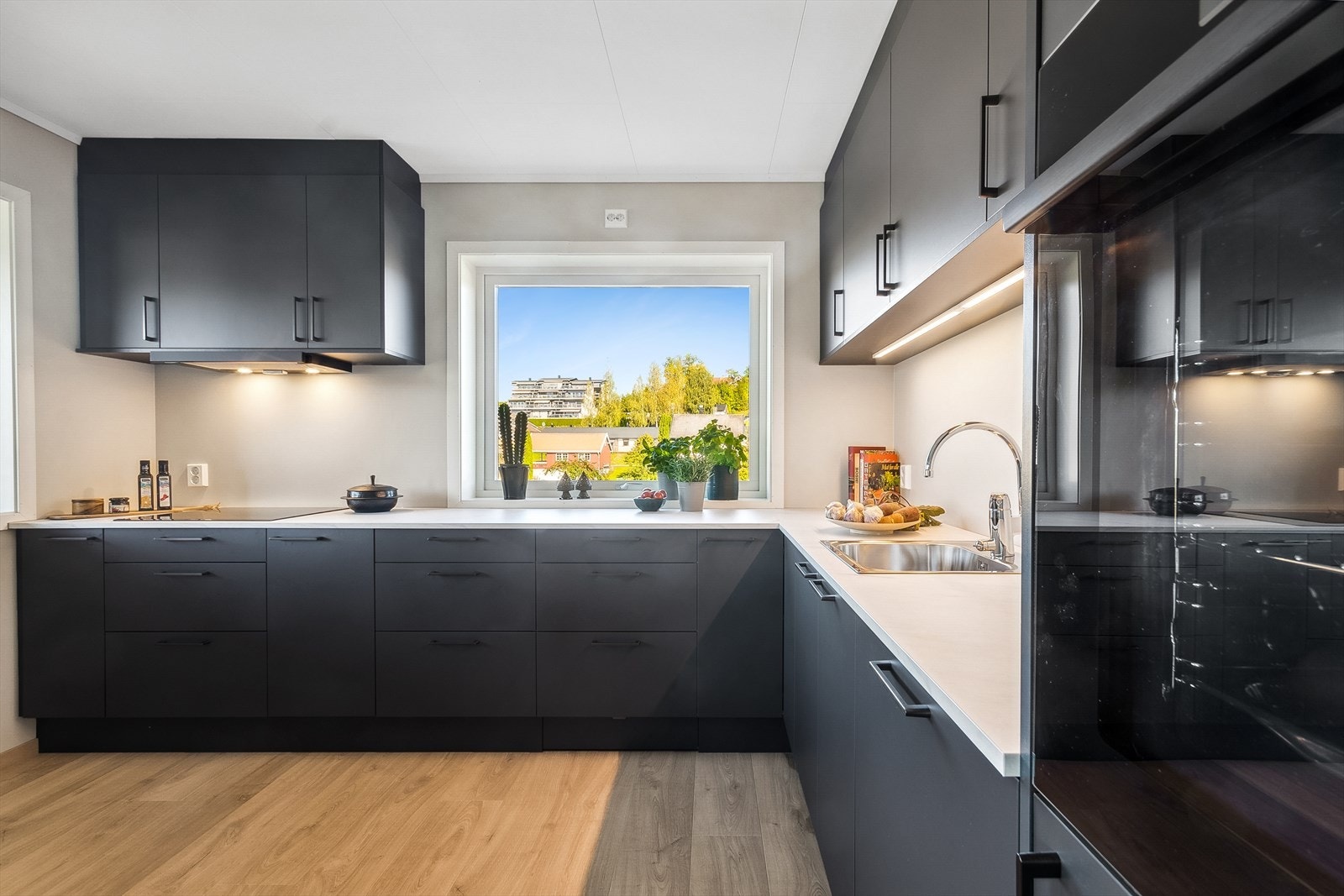 Lekkert og funksjonelt arbeidskjøkken fra Sigdal, hvor ingenting mangler. Kjøkkenet får rikelig med naturlig lys fra vinduet over benken, i tillegg til belysning montert under overskapene. Galleribilde