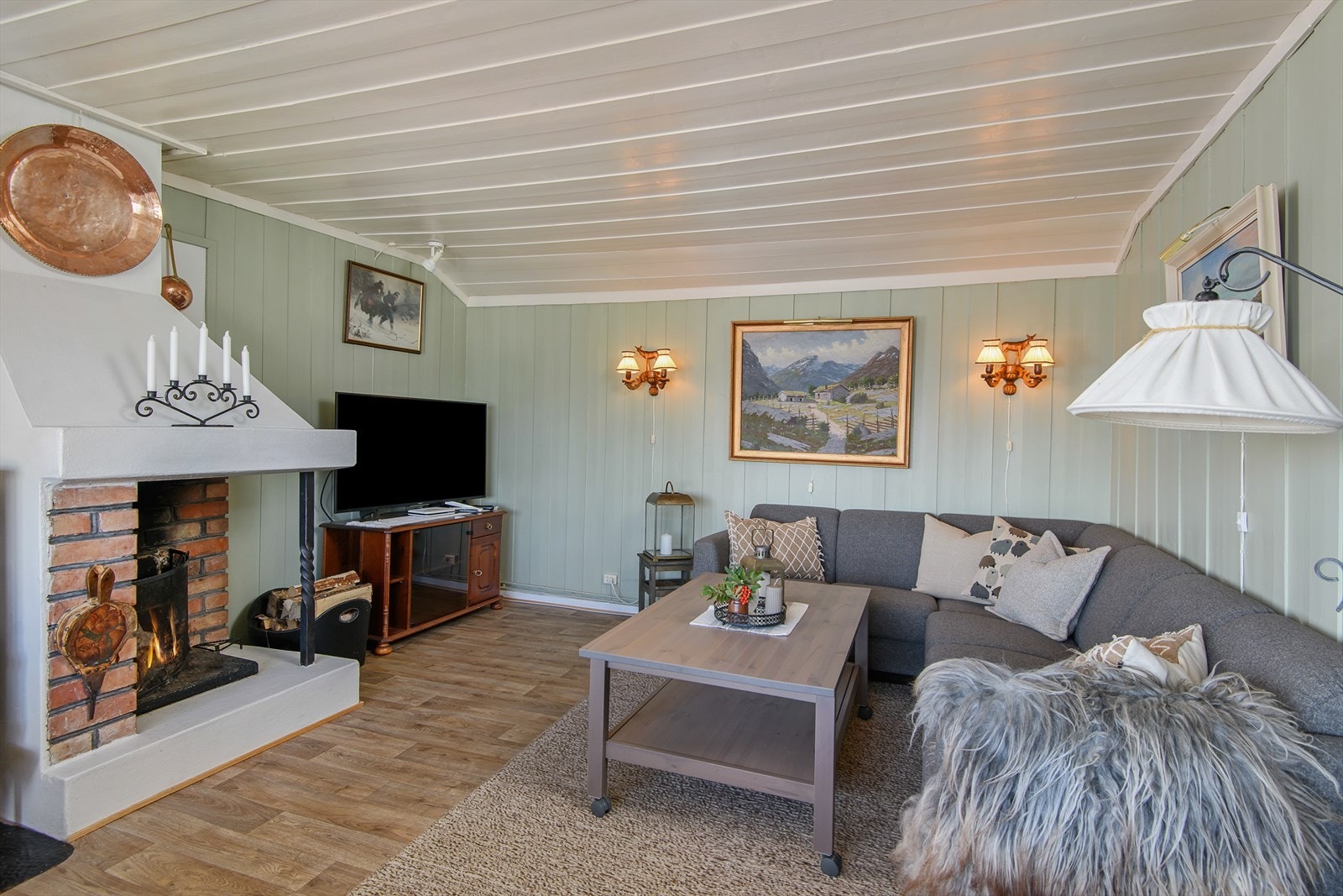 Sofaen er fint plasser ti forhold til peisen. Tak og vegger er malt i lyse og delikate farger. Galleribilde