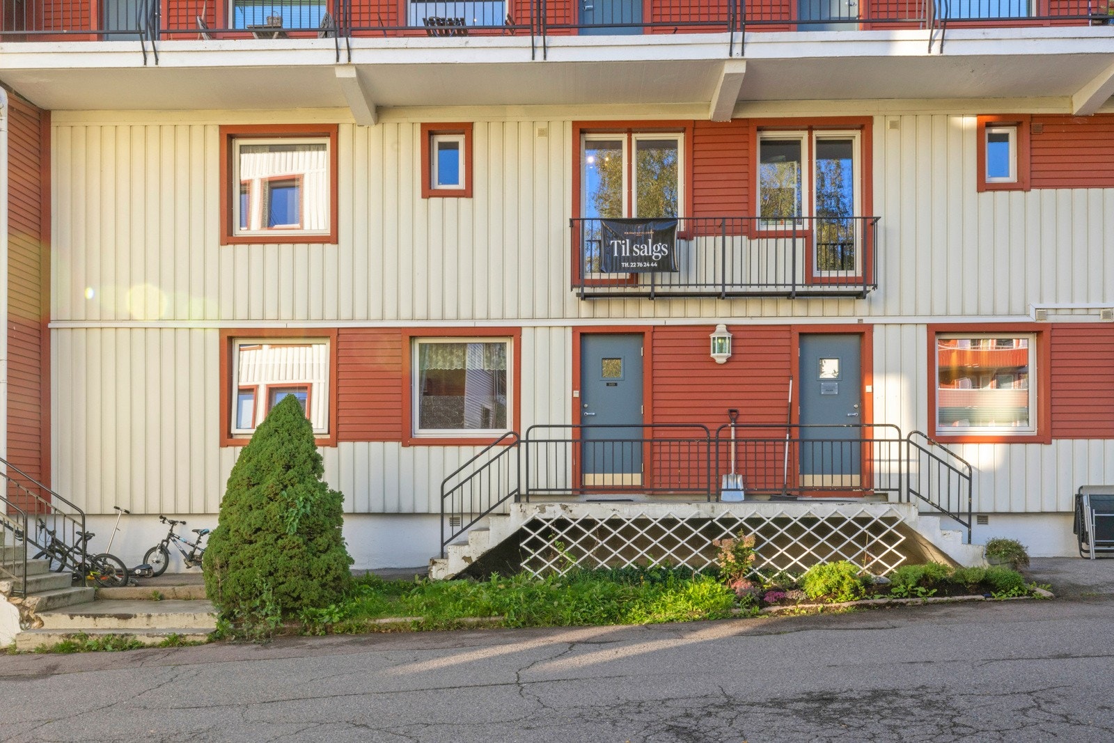 Opp til en grå inngangsdør med glassfelt er det støpt trapp med rekkverk Galleribilde