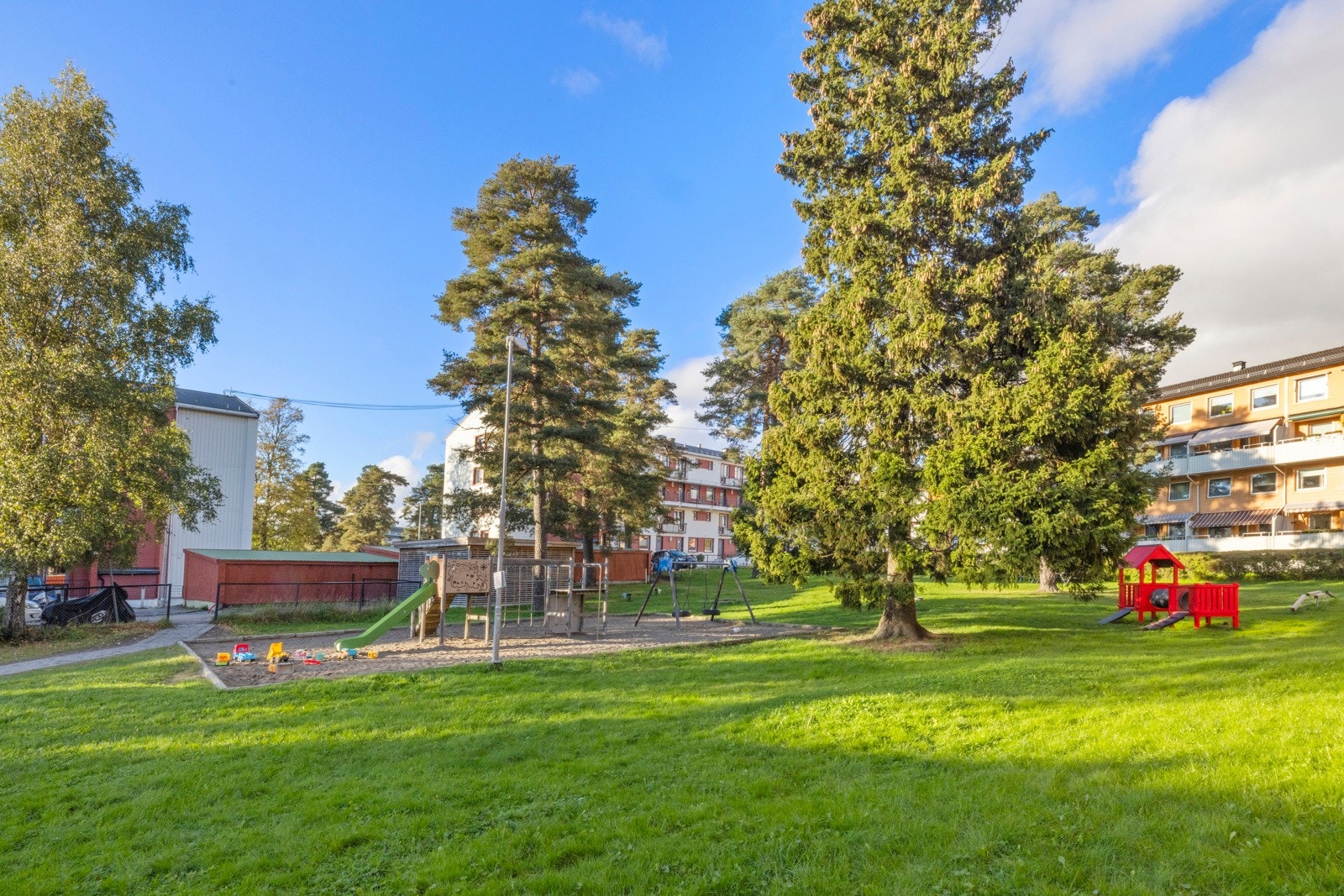 Godt skjermet blant bebyggelsen er det en sosial møteplass med flere sittebenker og en koselig lekeplass Galleribilde