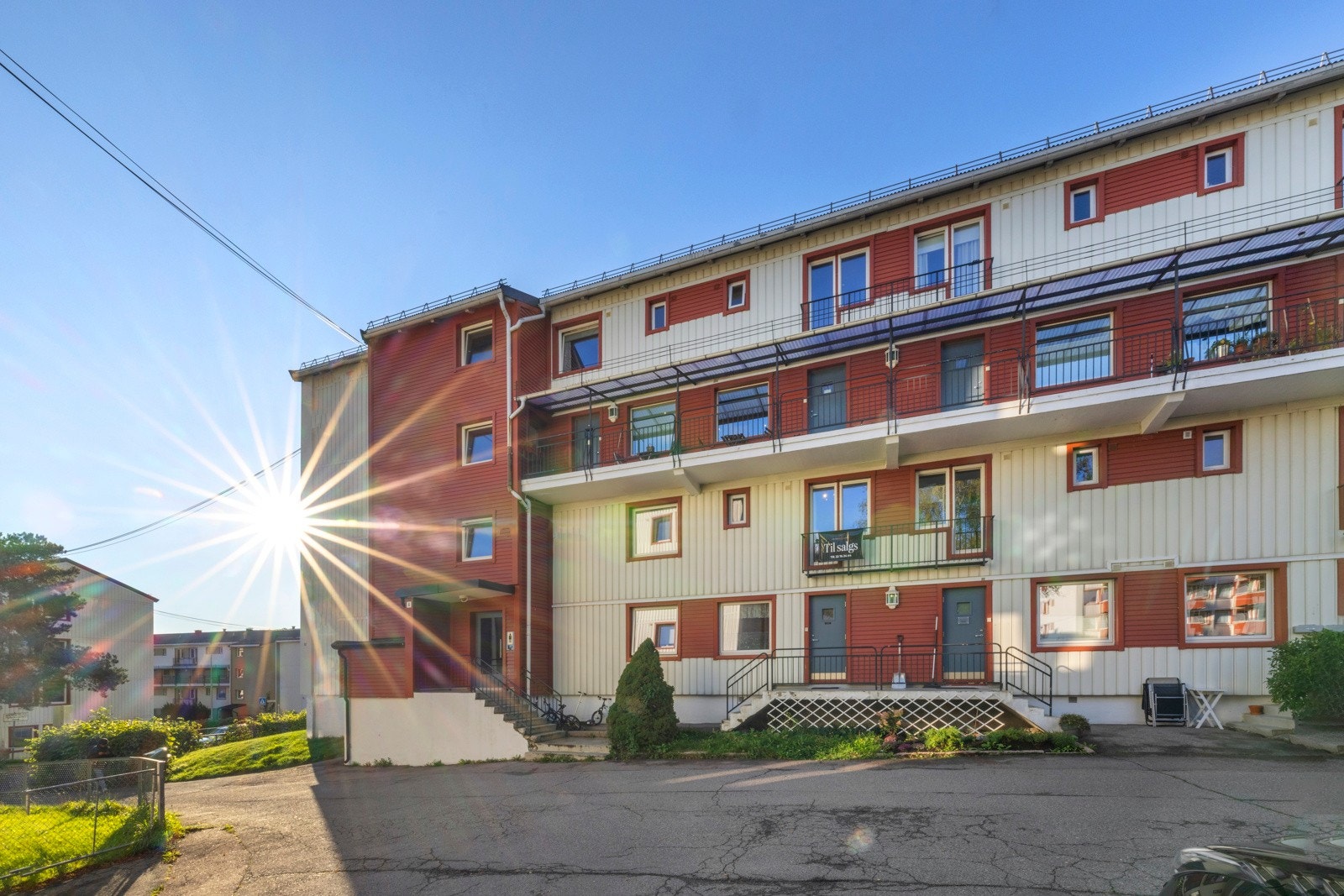 Leiligheten har egen inngang i første etasje og rett ved inngangspartiet er det asfaltert dekke med noe plass til sykler og sparkesykler Galleribilde