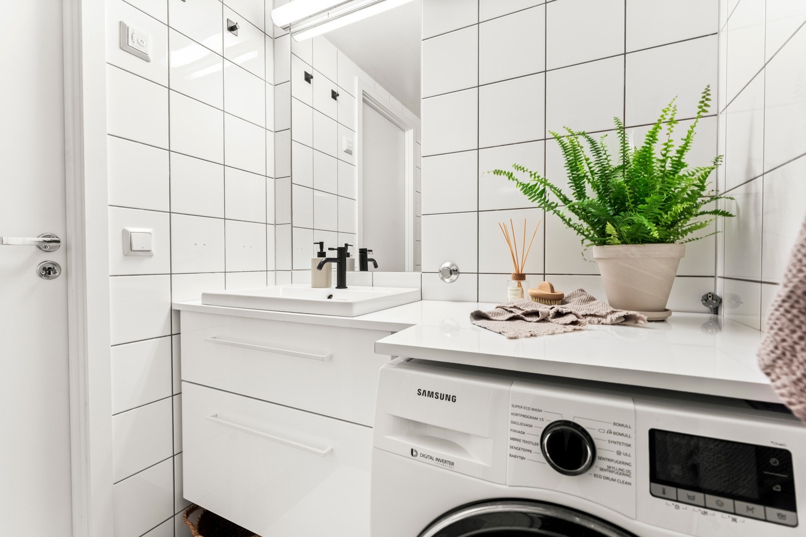 Baderomsinnredning bestående av benkeskap med glatte fronter samt speil og belysning over servant. Galleribilde