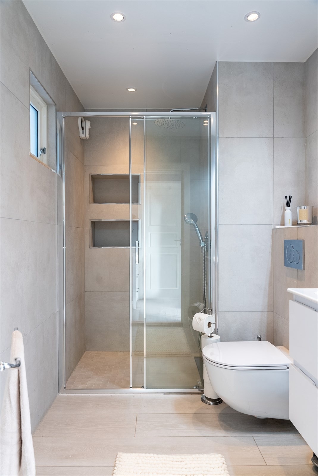 Moderne og delikat baderom med store fliser i behagelige beige toner, downlights i himling og varme i gulv. Galleribilde