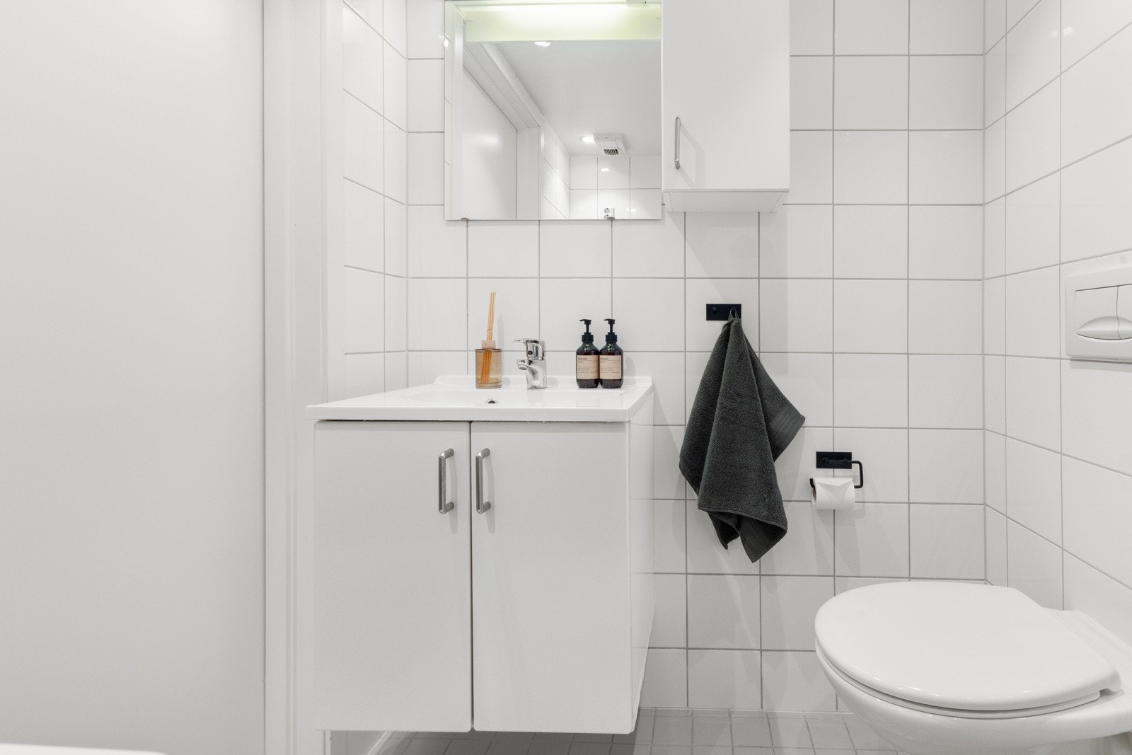 Badet har dusjhjørne med buede innfellbare glassdører og innredningen består av servant med underskap og et vegghengt toalett. Over servanten er det et vegghengt speil, skap, samt ekstra belysning Galleribilde
