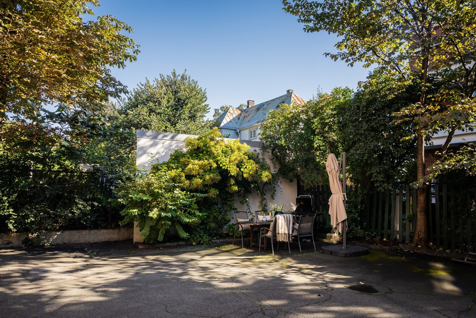 Idyllisk bakgård med sittegruppe, parasoll og felles gassgrill. Galleribilde