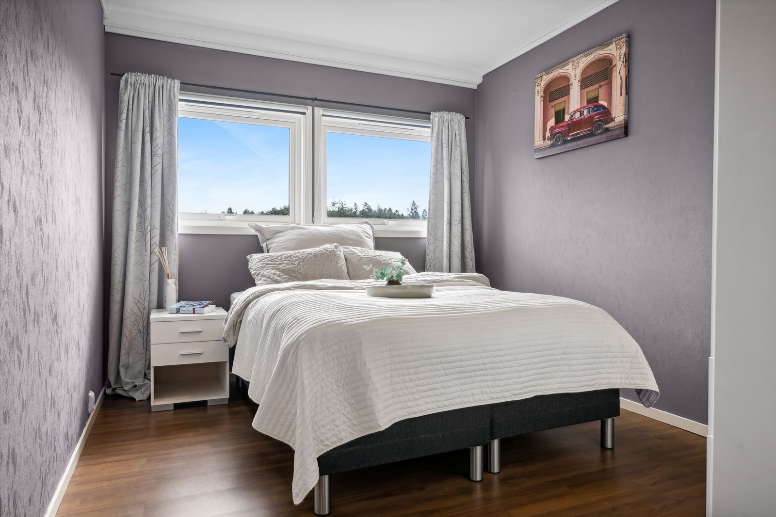 Romslig soverom med store gode vinduer og plass til bred seng med tilhørende nattbord Galleribilde