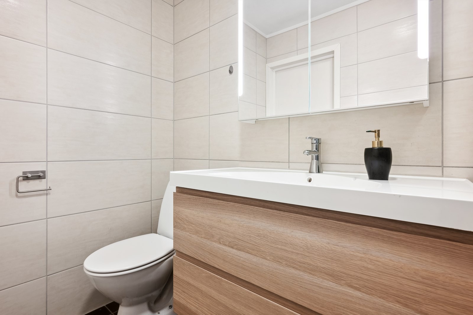 Over servant er det vegghengt skap med speilfronter og belysning Galleribilde