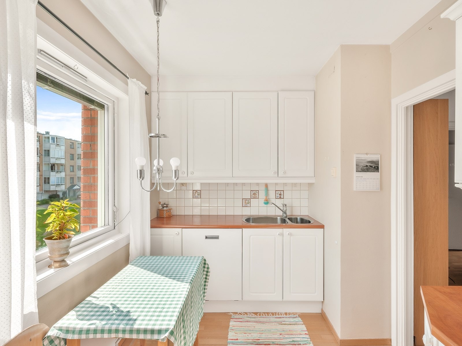 Lyst kjøkken med spiseplass og utsikt mot gårdsplassen Galleribilde