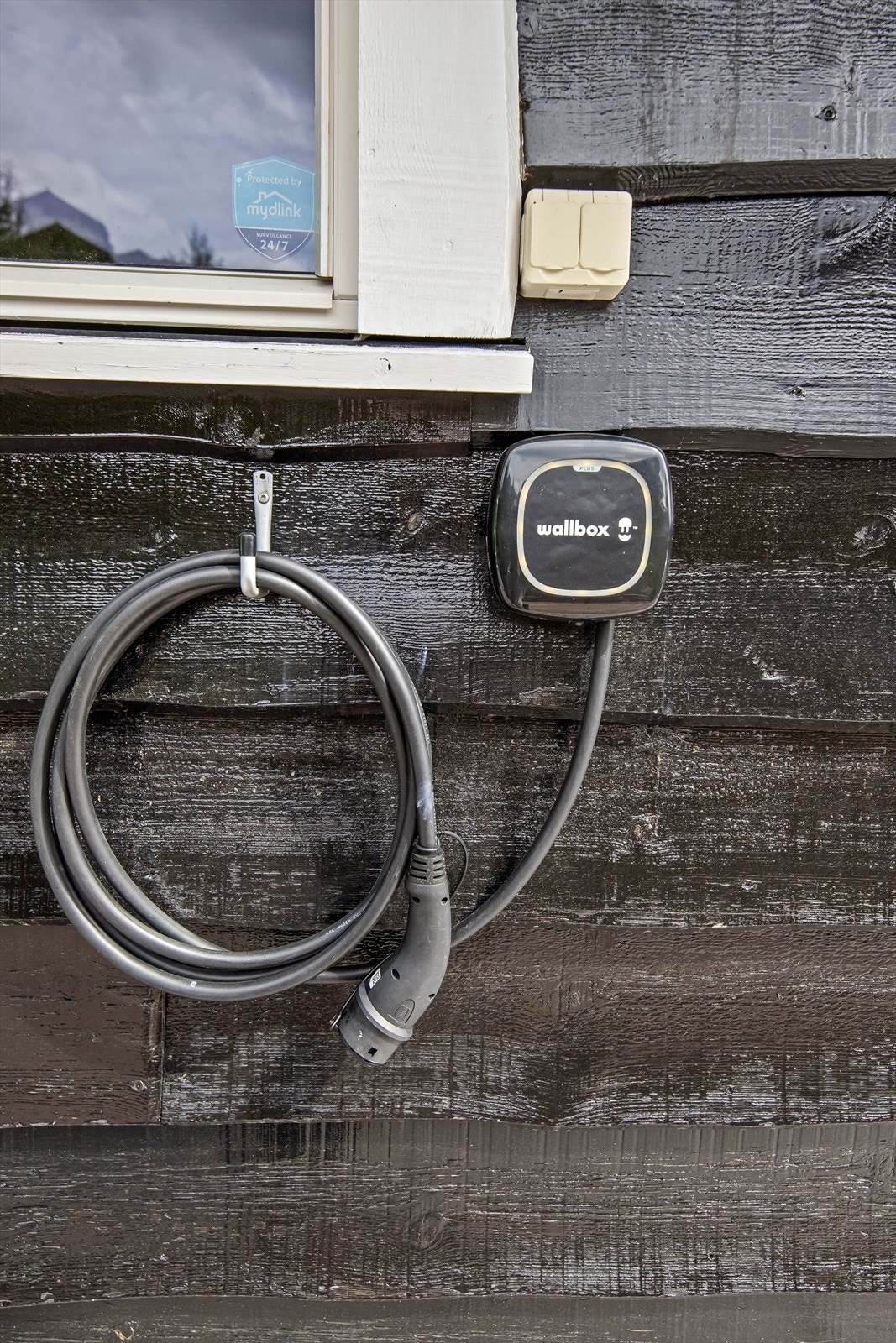 Elbil lader på hyttevegg ved parkering Galleribilde