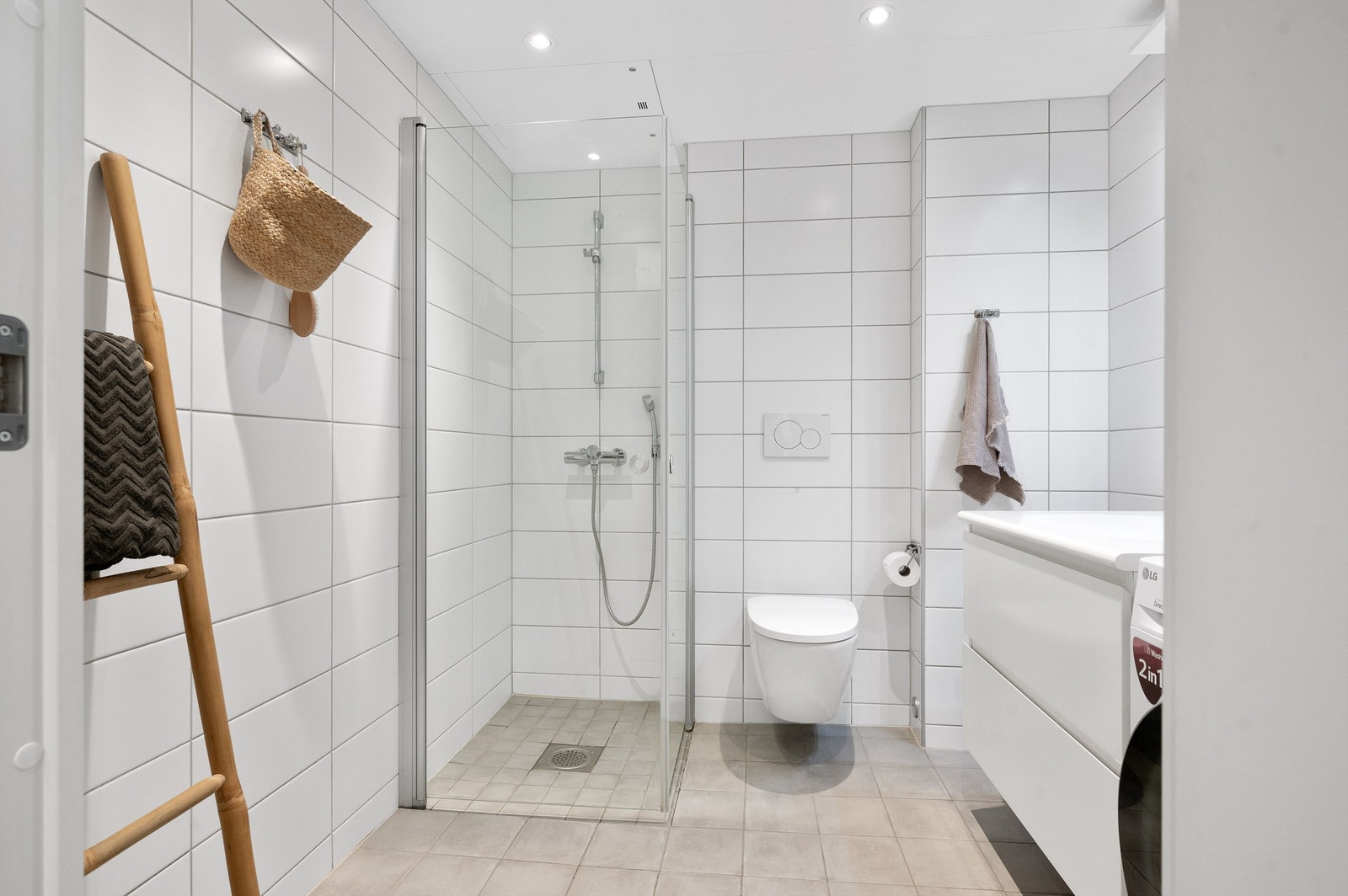 Delikat og meget romslig bad med flislagte gulv- og veggflater samt varme i gulv og downlights i himling Galleribilde