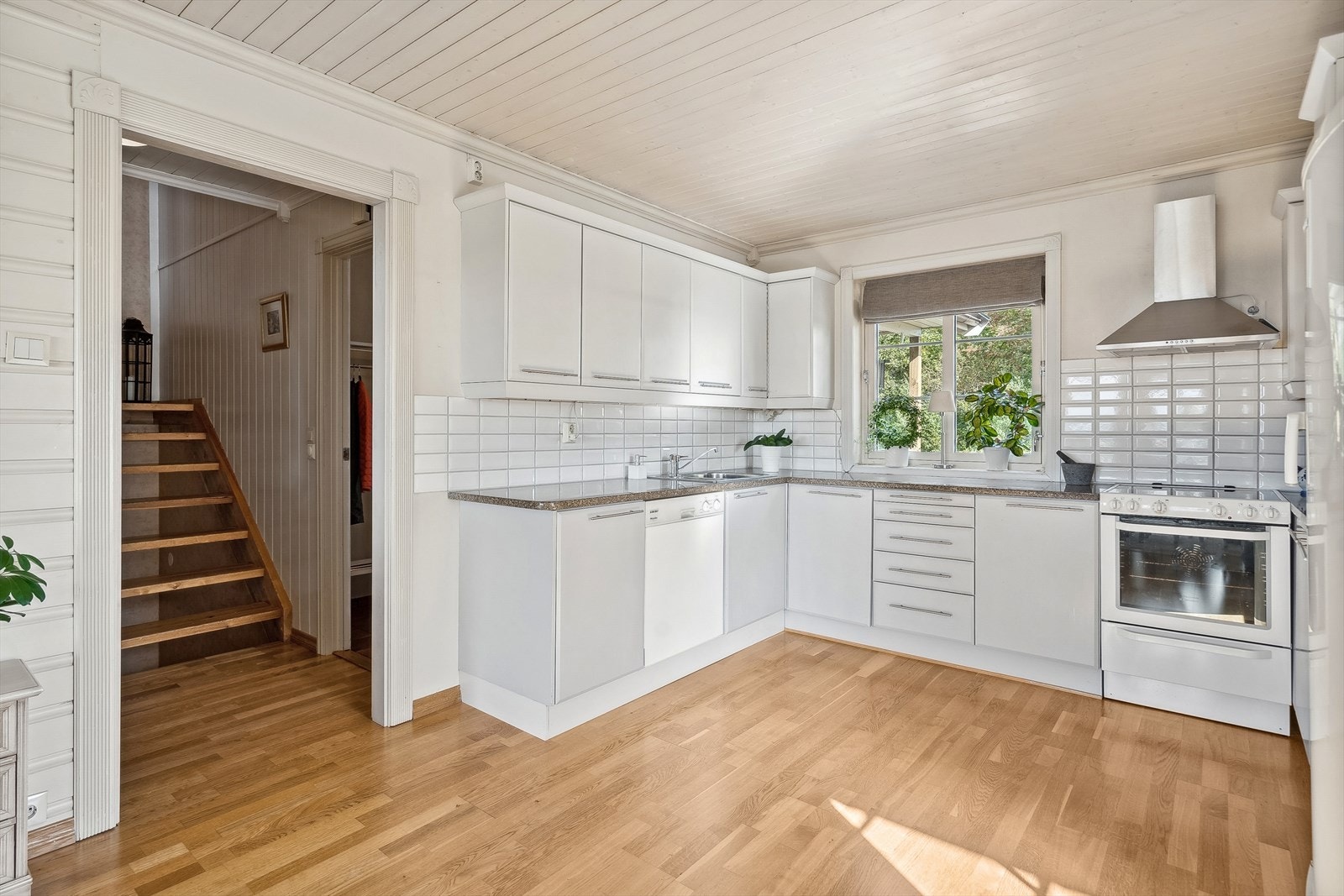 Fra entréen til trappegang og videre i åpen løsning til kjøkkenet som har godt med innredning med lyse, tidløse fronter Galleribilde