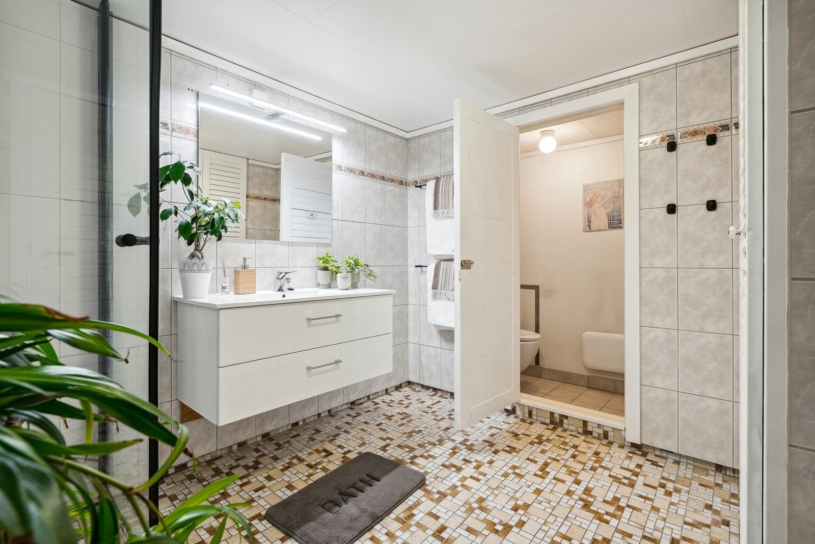 Bad i underetasje innredet med benkeskap med nedfelt porselen servant, speil med belysning over og dusjhjørne. Toalett er i et eget rom med inngang fra bad Galleribilde