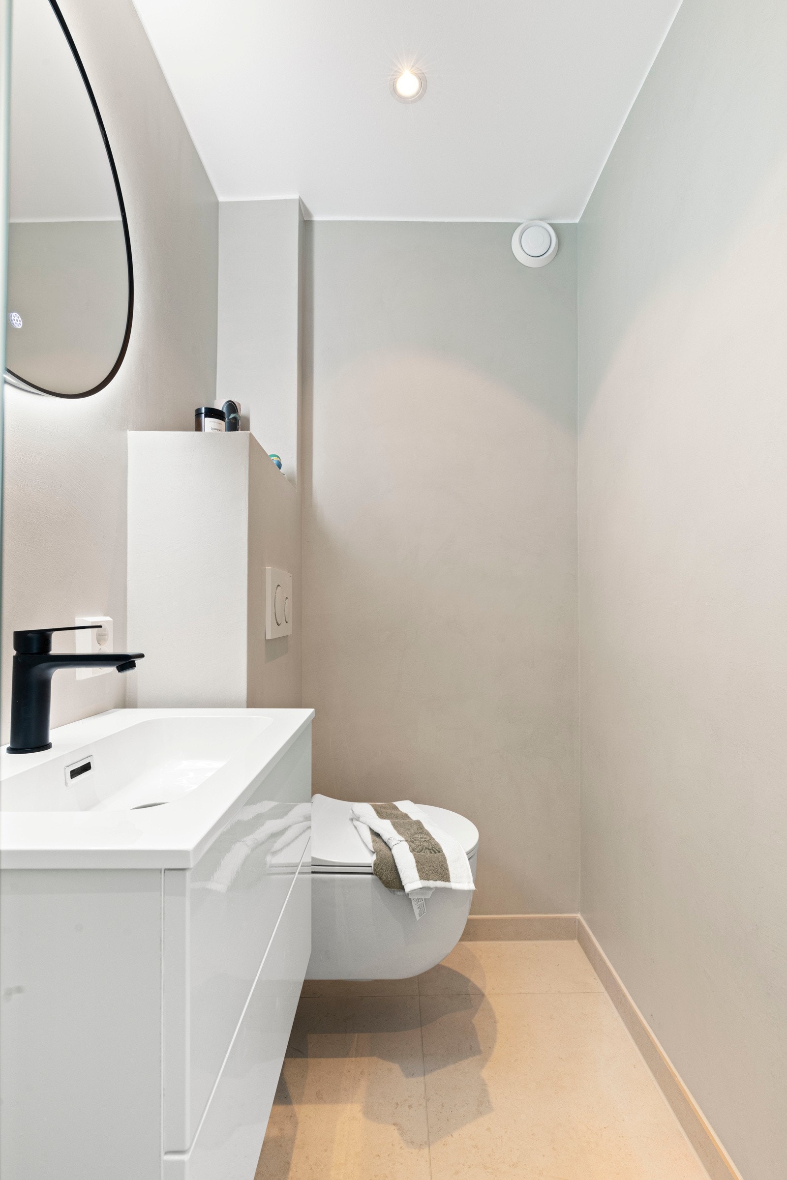 Badet består av vegghengt toalett, dusjhjørne med to stk foldbare glassdører og ny innredning med slette fronter og skuffeløsning. Tidsriktig speil med lys. Mikrosement på veggene og downlights i himling. Galleribilde