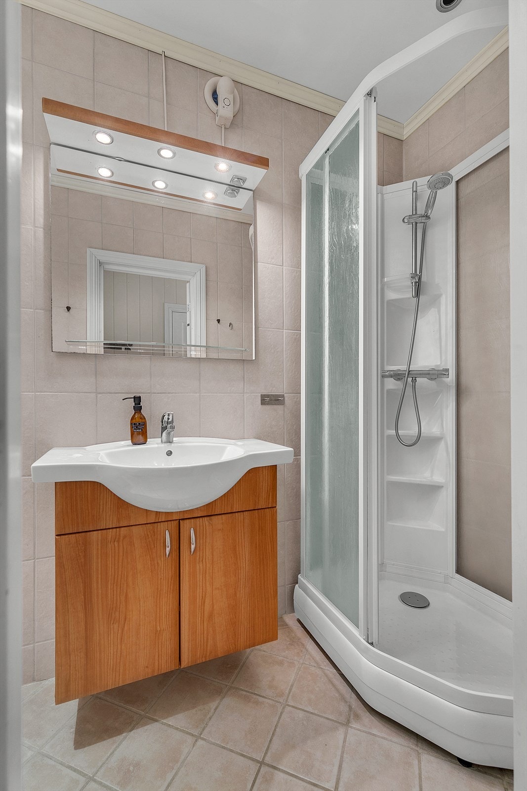 Flislagt bad med servantskap, dusjkabinett og varme i gulv. Galleribilde