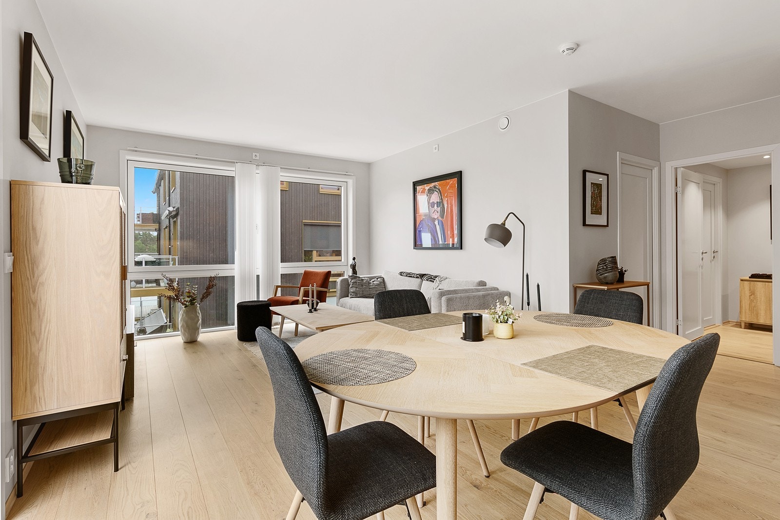 Stue og kjøkken i åpen løsning med naturlig spisedel mellom miljøene Galleribilde