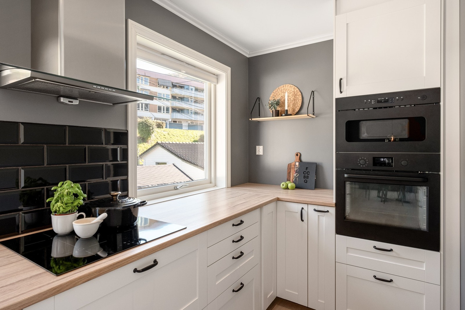 Kjøkkenet er levert av IKEA og har takhøy innredning med klassiske, hvite profilerte fronter og keramiske fliser over deler av benkeplate. Galleribilde