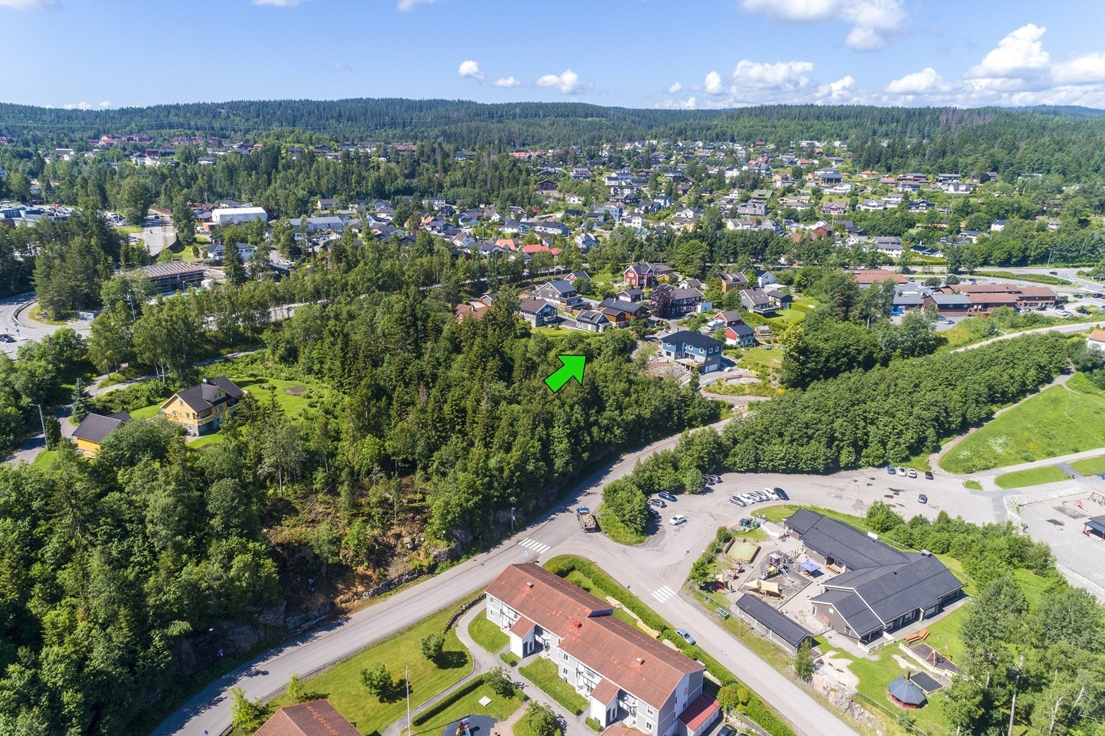 Tomten ligger i etablert område nær Hagan senter med flere servicetilbud, skole og barnehage i gangavstand fra boligen (bygning neders til høyre på bildet er barnehagen) Galleribilde