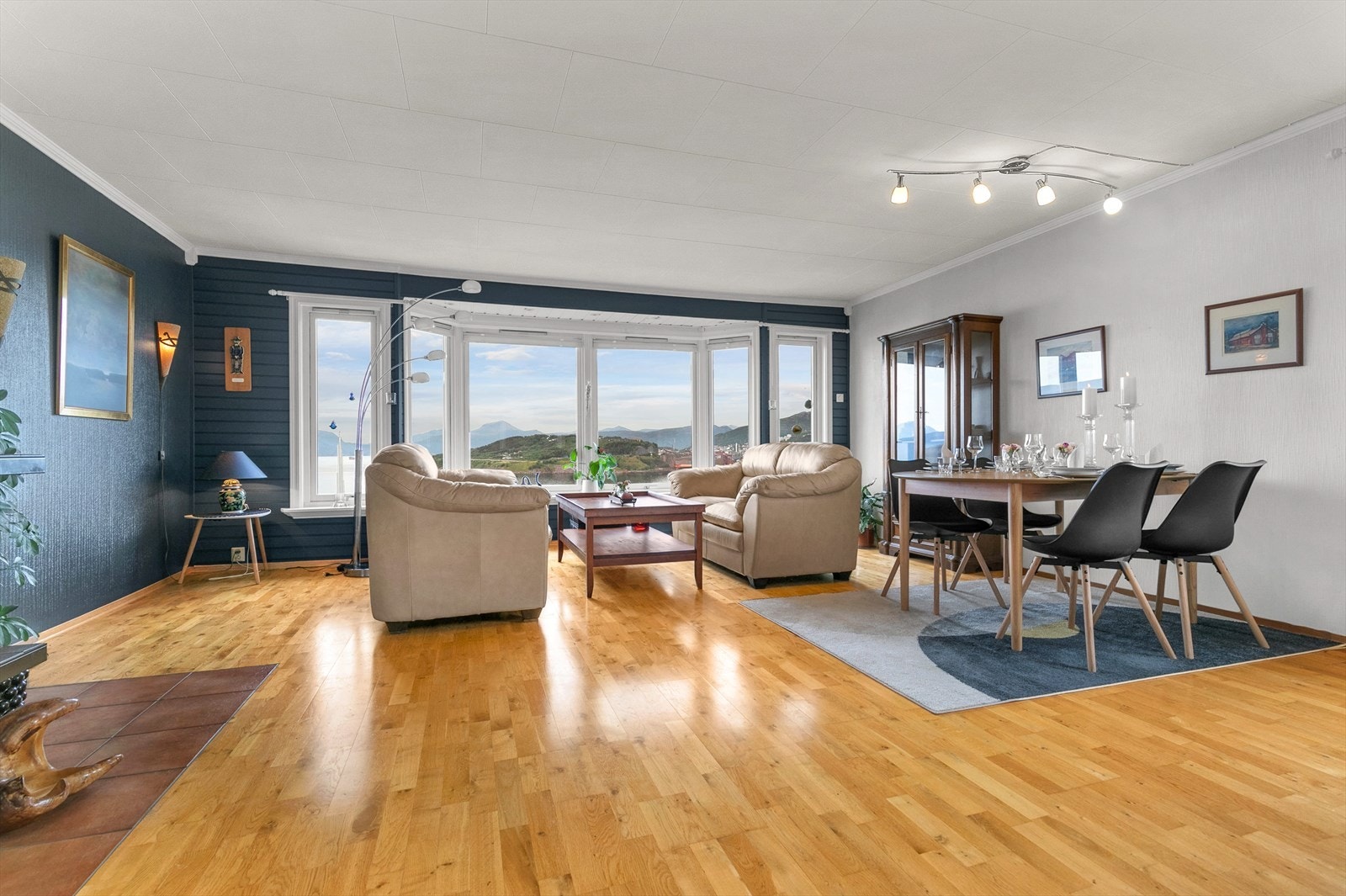 Romslig stue med store vindusflater som byr på flott utsikt over Ofotfjorden, Narvik og Narvik havn. Galleribilde