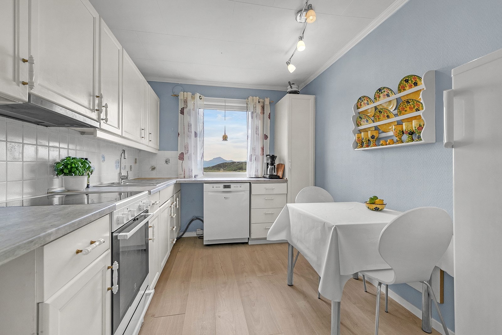 Lys kjøkkeninnredning med flis over benk. Galleribilde