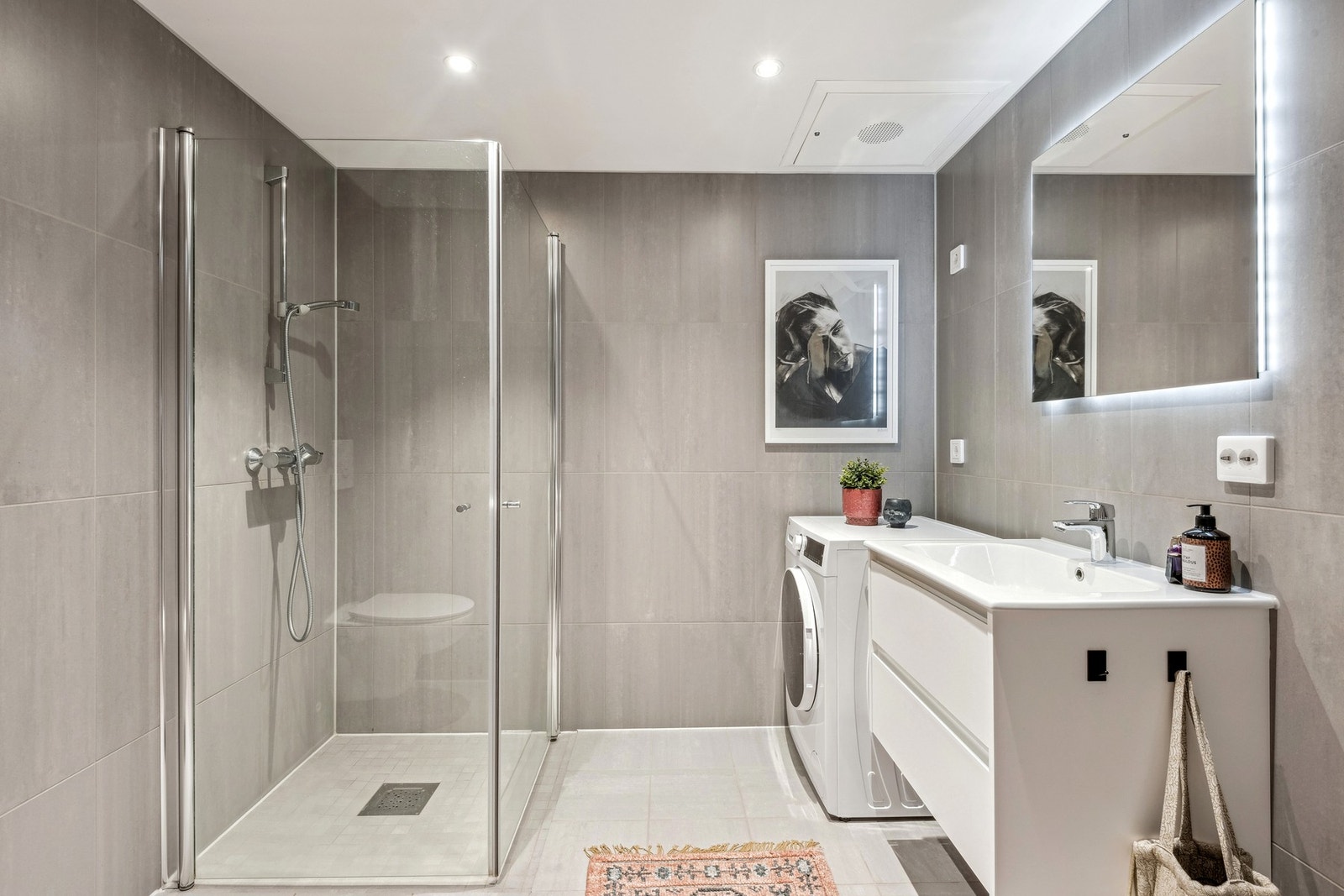 Badet inneholder veggmontert wc, dusjhjørne, baderomsinnredning og opplegg for vaskemaskin Galleribilde