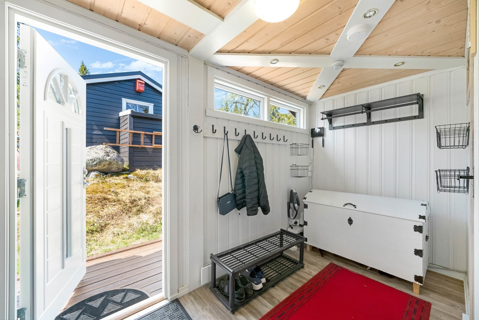 Du ønskes velkommen inn i en romslig entrè med laminat på gulv og lysmalt panel på vegger. Galleribilde