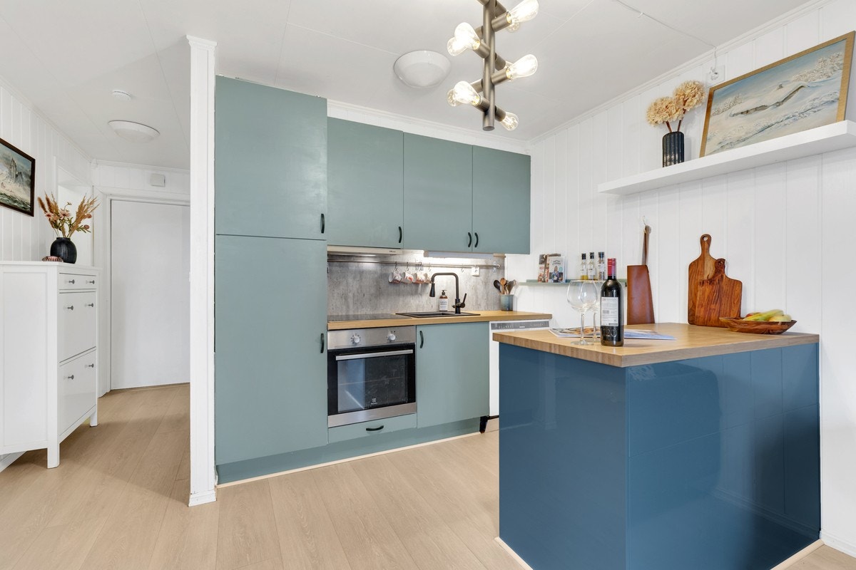 Åpen kjøkkenløsning med glatte fronter og benkeplate av tre. Kjøkkenøyen skaper et naturlig skille mellom kjøkken og stue. Galleribilde