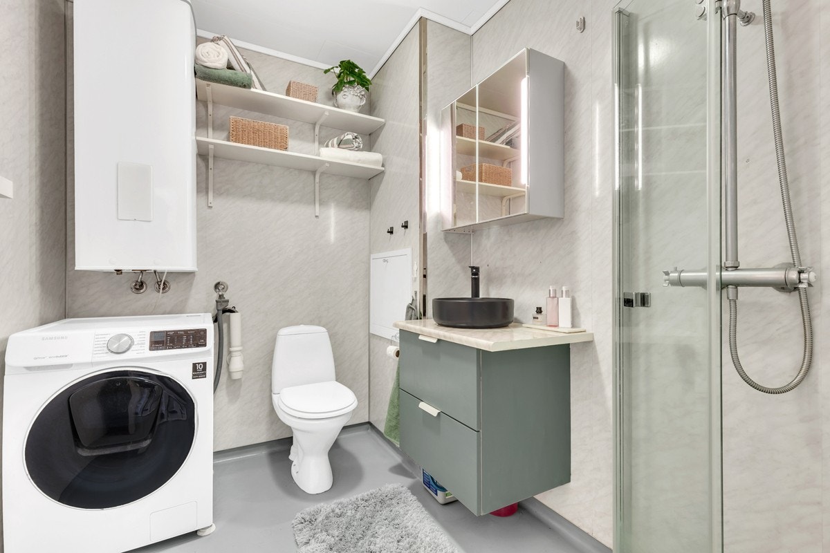 Badet har vegghengt servantinnredning, speilskap med lys, dusjhjørne og toalett, samt opplegg for vaskemaskin. Galleribilde