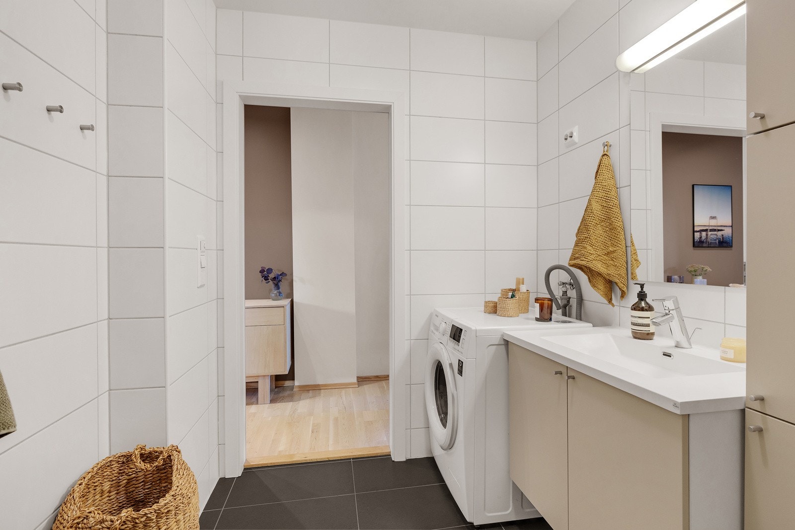 Badet har et tidløst uttrykk med store, mørke gulvfliser og lyse veggfliser. Galleribilde