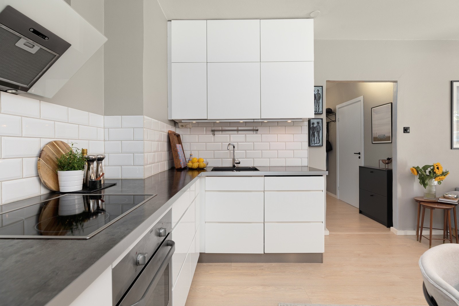 Kjøkkeninnredning med hvite grepsfrie fronter, overskap med benkebelysning og fliser på vegg Galleribilde