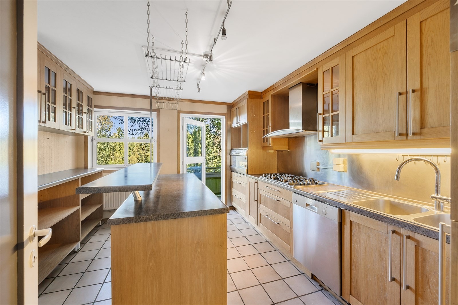 Separat og romslig kjøkkenrom med beskyttende fliser på gulv og praktisk kjøkkenøy Galleribilde