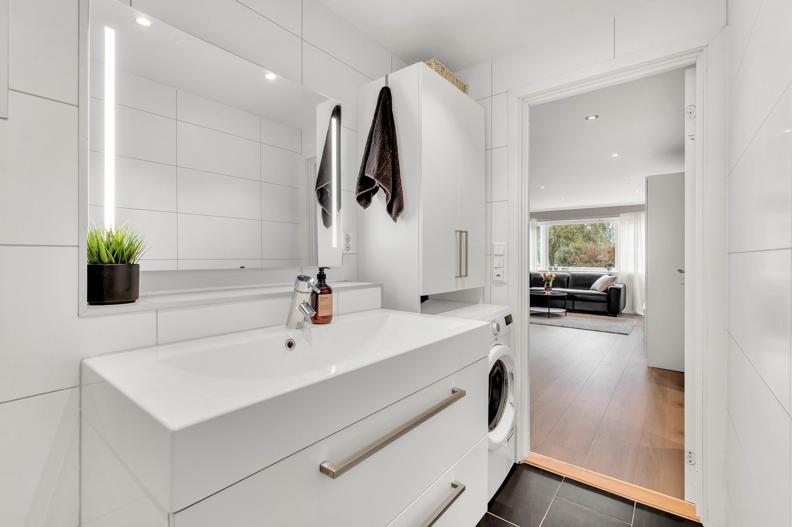 Badet har eget opplegg for vaskemaskin, vegghengt WC, dusjhjørne, servant og en moderne baderomsinnredning med mye lagringsplass. Galleribilde