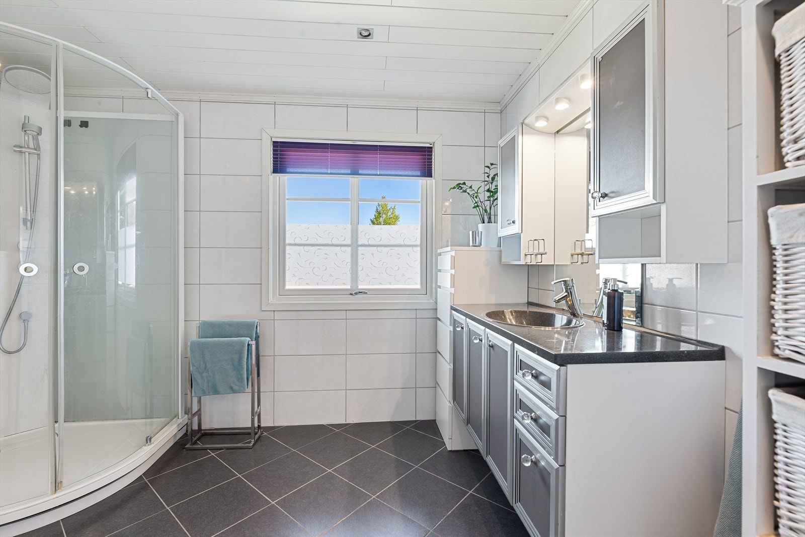 Videre er badet innredet med speil med belysning, dusjkabinett og toalett som er delvis adskilt med en delevegg. Galleribilde