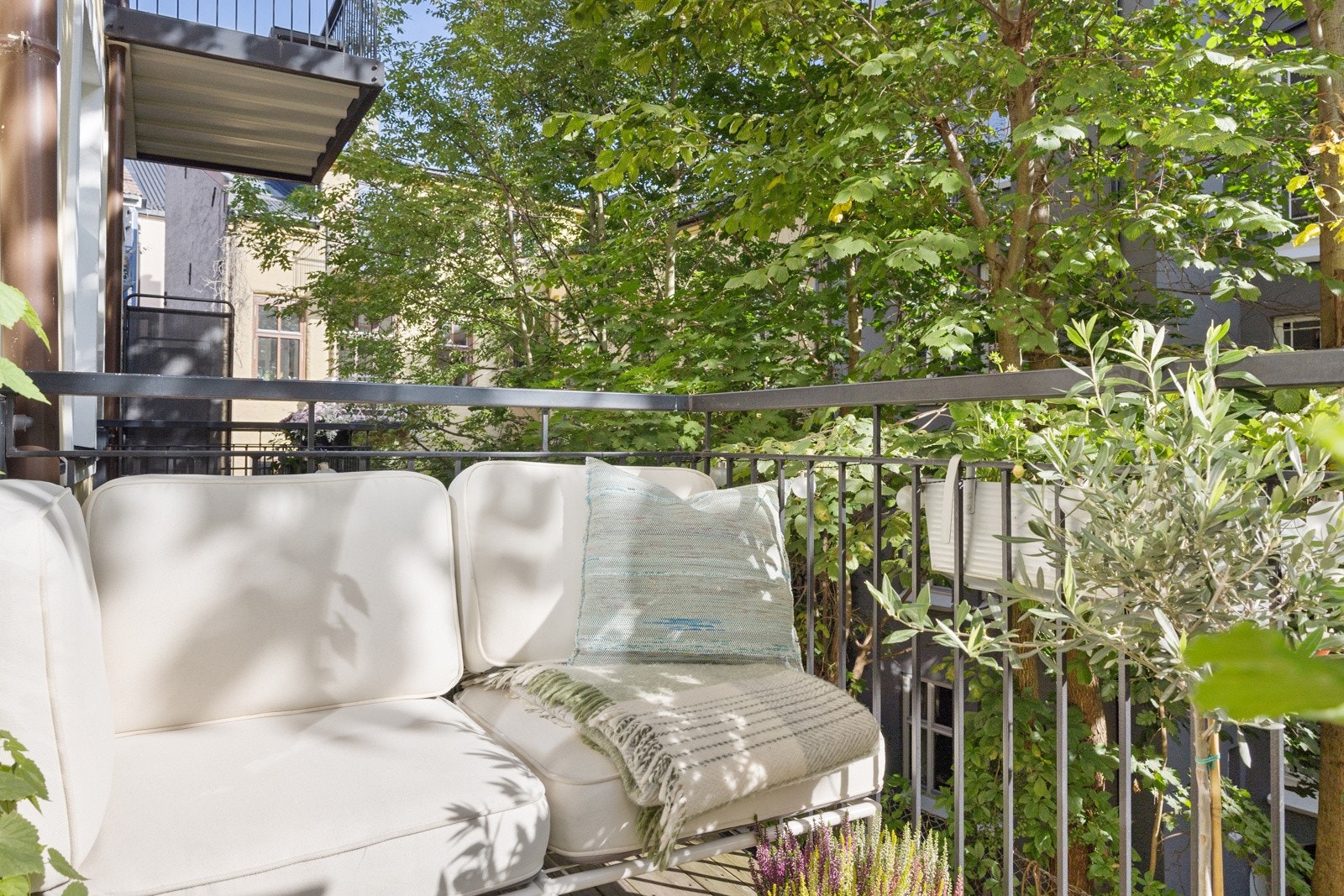 Utgang fra stuen til hyggelig balkong mot frodig gårdsrom. Galleribilde