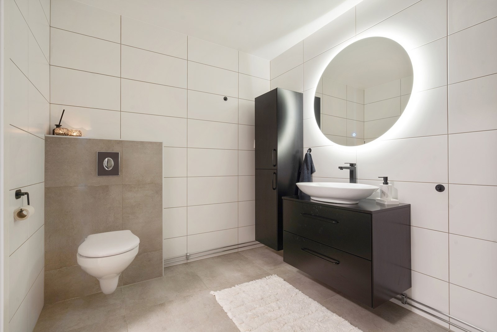 Badet er velutstyrt med behagelig varme i gulv, servantskap, speil med integrert belysning og vegghengt toalett. Det er også separat vaskerom i leiligheten. Galleribilde