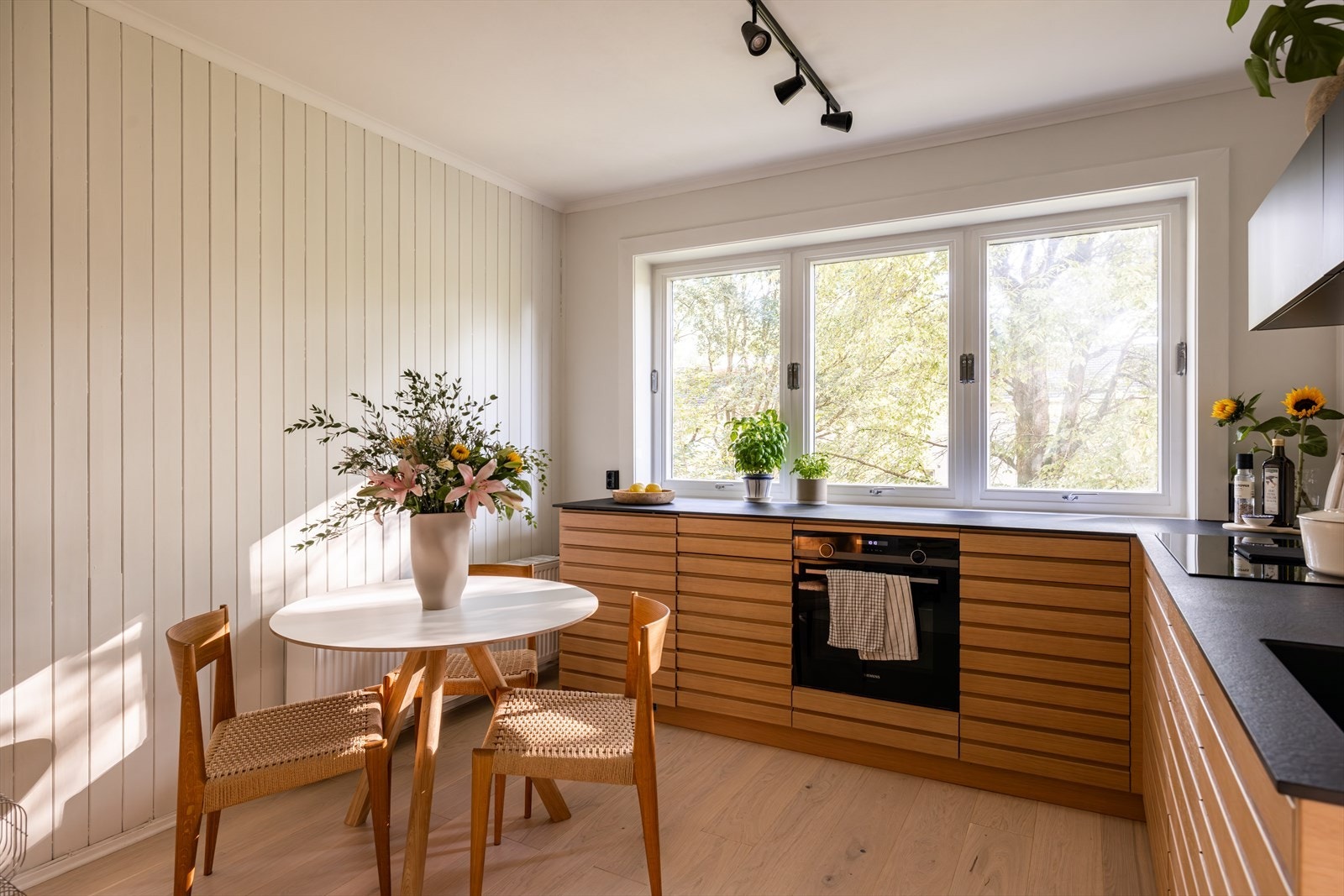 Leiligheten har en lekkert designet kjøkkeninnredning fra Kvik, installert i 2020, med vakre eikefronter som utstråler dansk design som kombineres perfekt med sort, tynn, elegant benkeplate og sort, matt overskap. Galleribilde