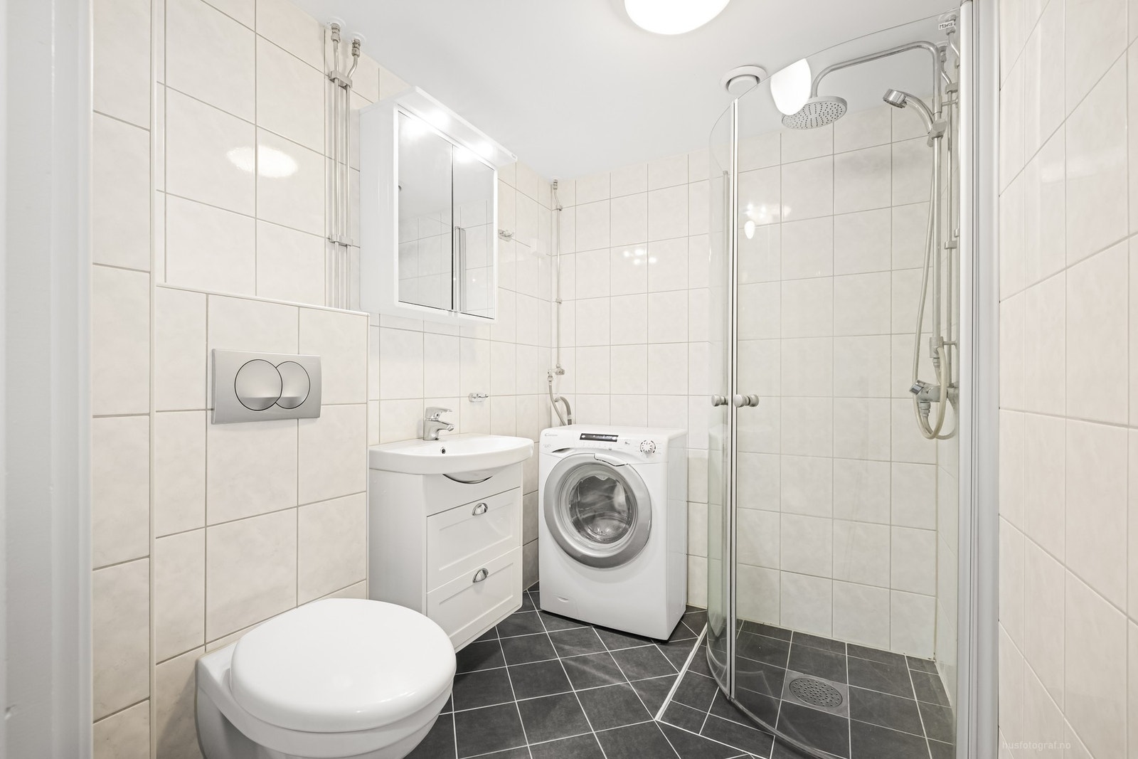 Flislagt bad med dusjhjørne, servant , wc og opplegg til vaskemaskin. Galleribilde