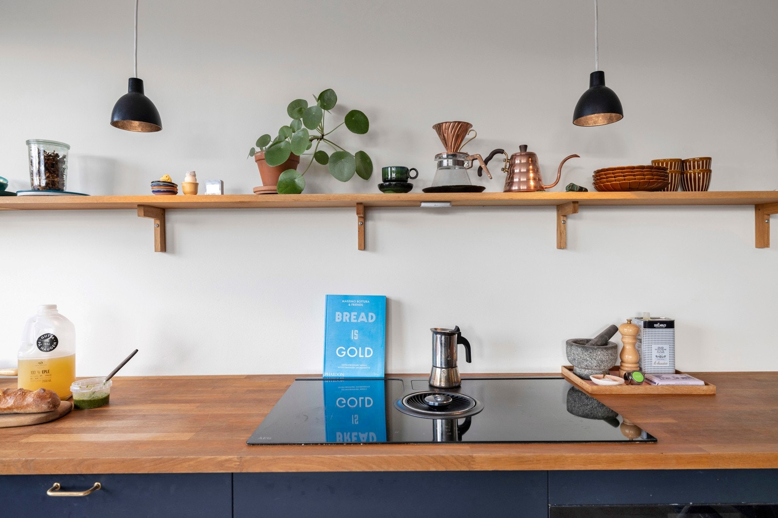 Induksjonstoppen fra AEG har integrert kullfilterventilator. Det er fine pendellamper fra Louis Paulsson over benken. Galleribilde