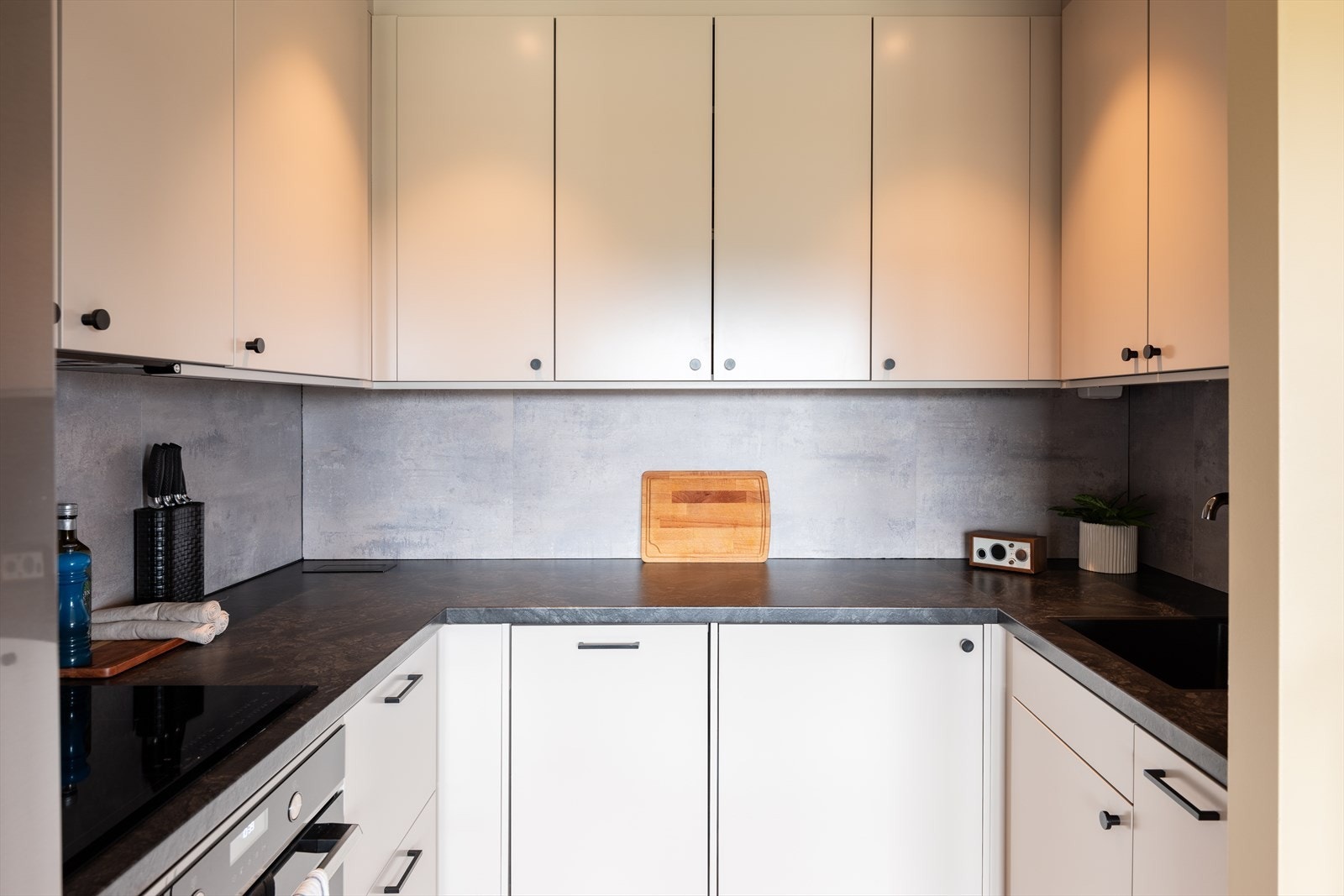 Kjøkken fra Epoq med lakkerte fronter uten profil, laminat benkeplate og våtromsplater på vegg over benkeplate. Galleribilde