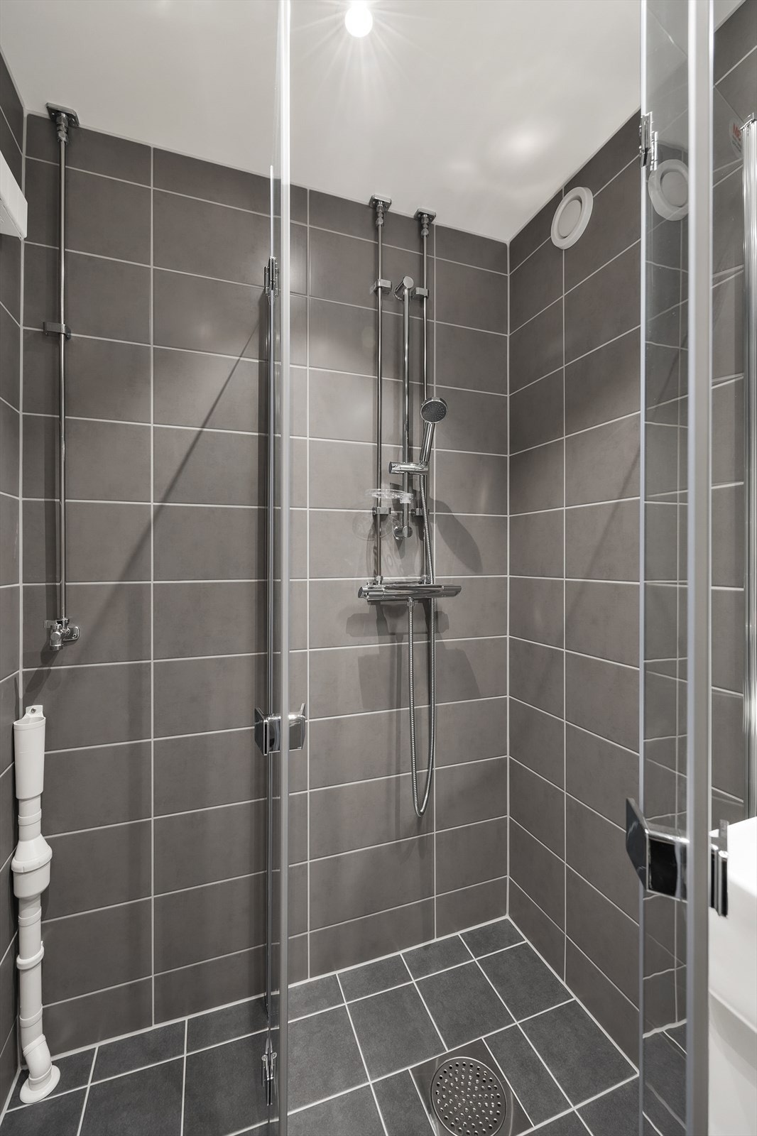 Innredningen består av vegghengt toalett, servant med underskap, speil med overlys, og dusjhjørne med innfellbare glassdører. Det er opplegg for vaskemaskin Galleribilde