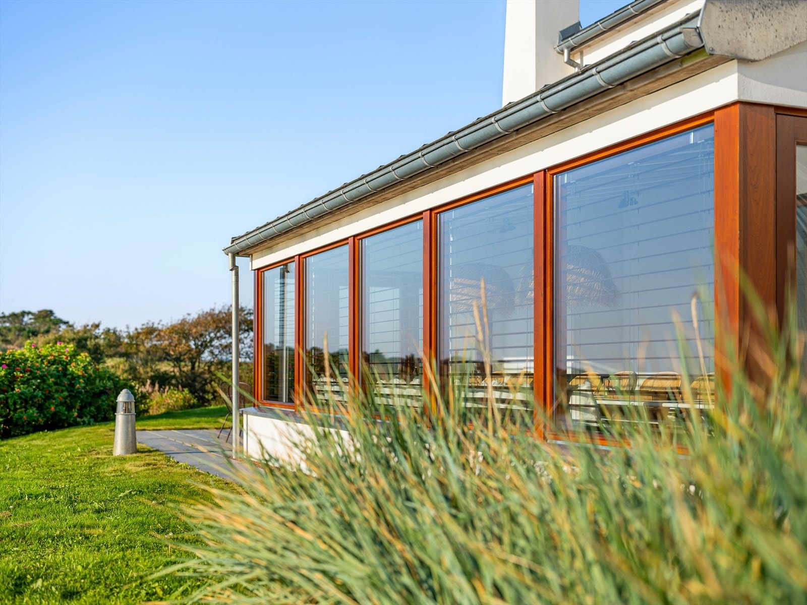 Solrike plattinger på flere sider av fritidsboligen. Nydelig bruk av ulike materialer i pene kontraster. Skifer, stål, naturstein, mur, sink, teak, tilpasset beplantning. Galleribilde