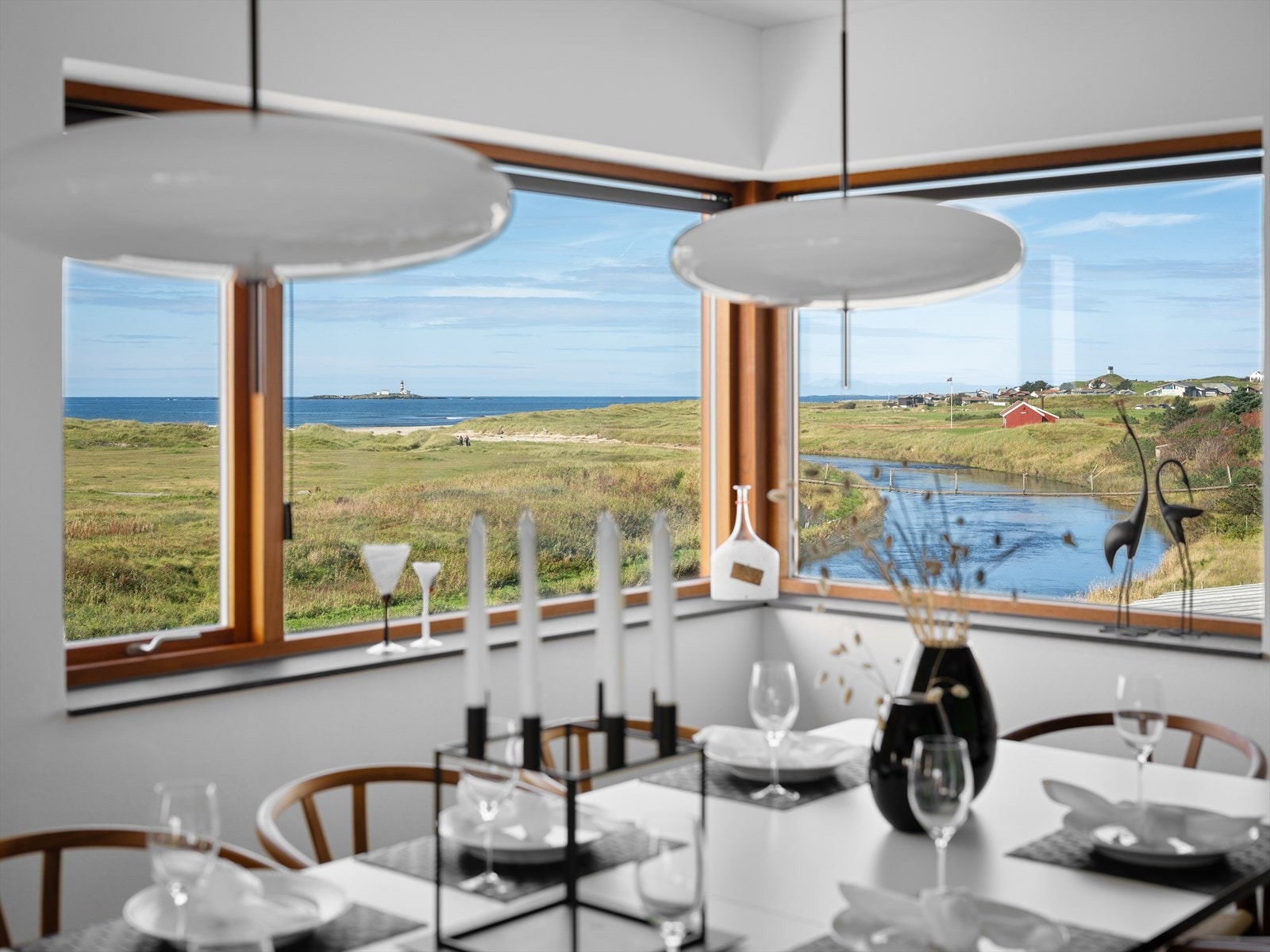 Utsikten er formidabel, uansett om du nyter den i godstolen i 1. etg, med familien rundt langbordet i hagestuen i u. etg eller fra sengen en tidlig morgen. I horisonten ligger havet med Feistein fyr langt der ute, nesten som innrammet i teak. Galleribilde