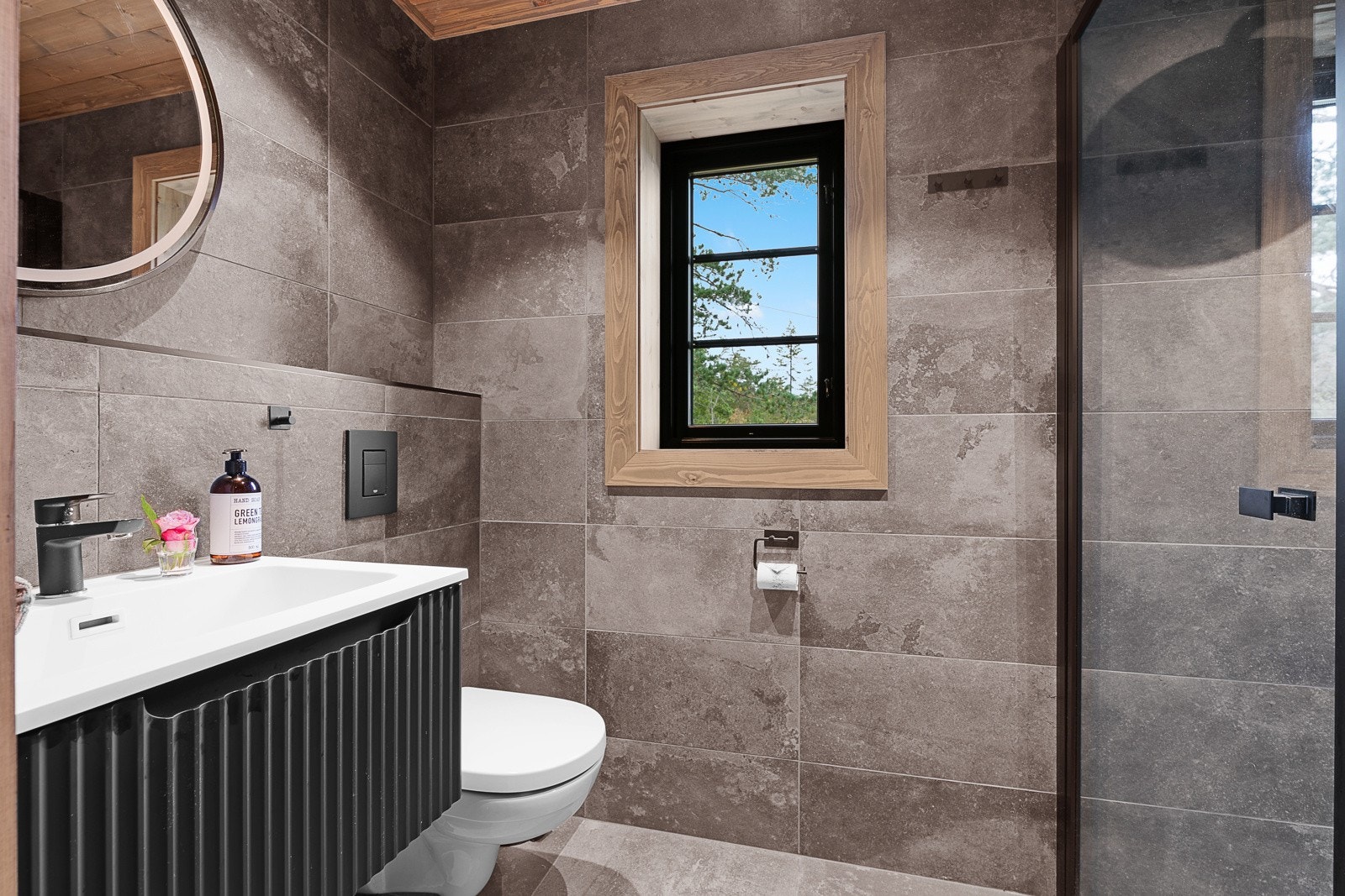 Flislagt bad med vegghengt toalett og servant med innredning Galleribilde