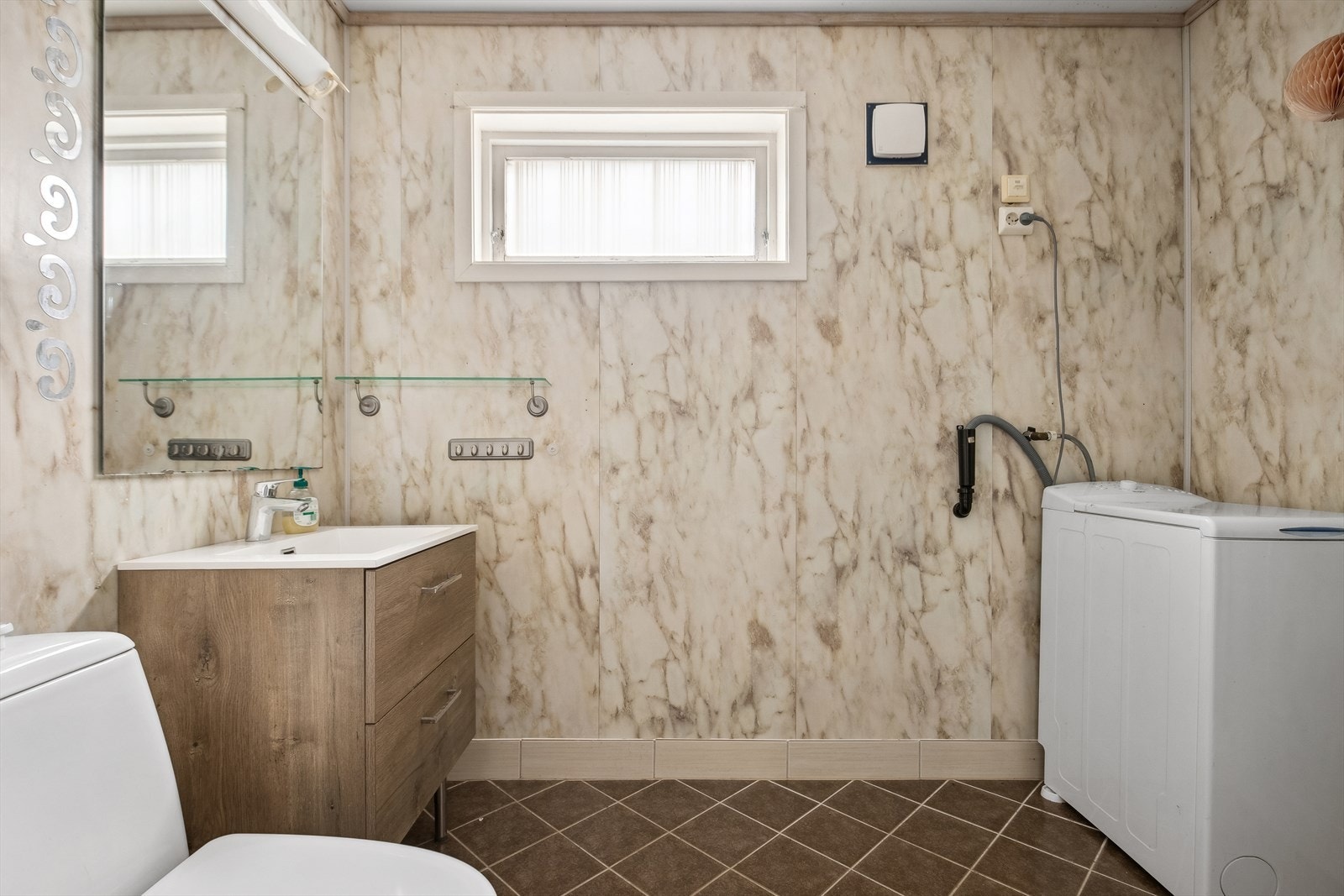 Badet er innredet vask montert i skuffeseksjon, dusjkabinett og toalett. Ventilasjon via ventil i vegg. Galleribilde