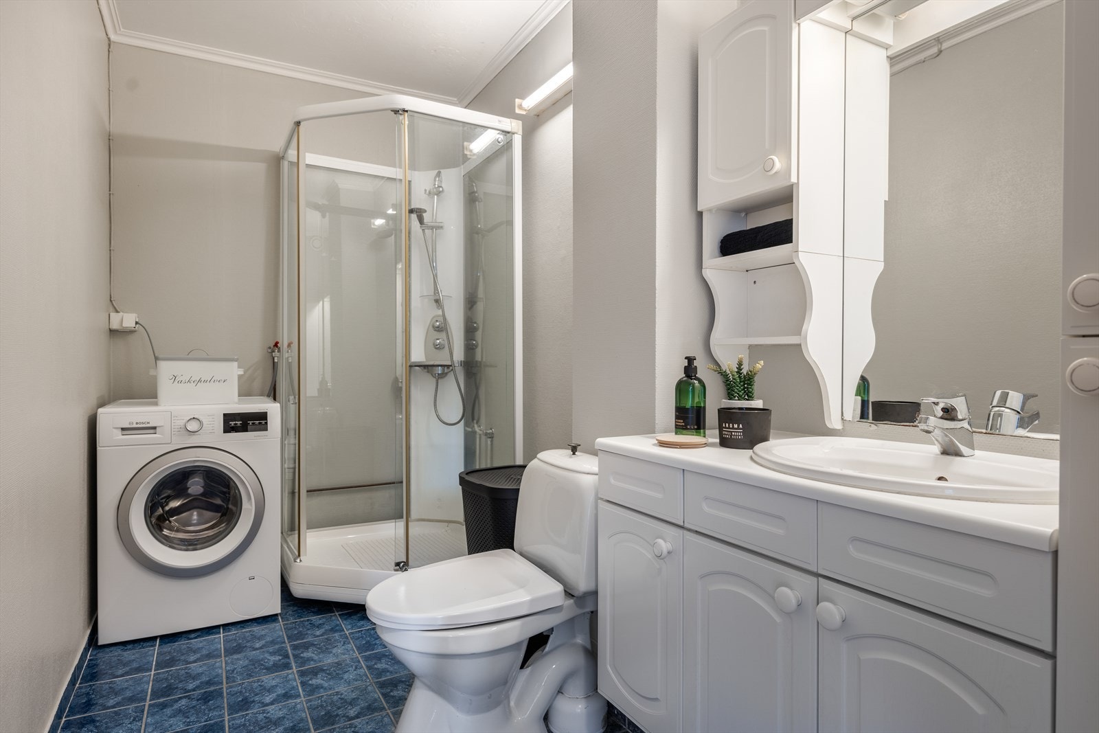 Lys baderomsinnredning med fronter i profilert utførelse og servant nedfelt i benkeplate, speil og overlys med el-stikk. Galleribilde